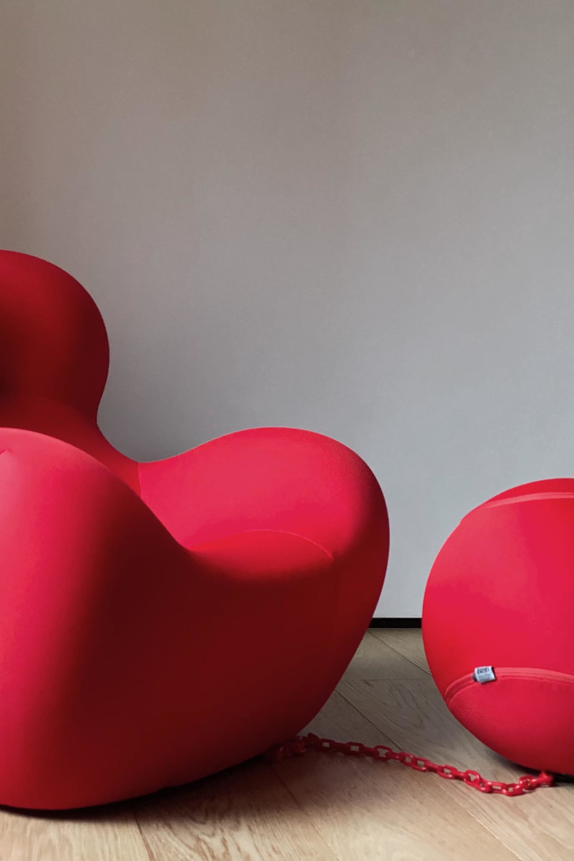 Two red, modern armchairs against a plain wall.