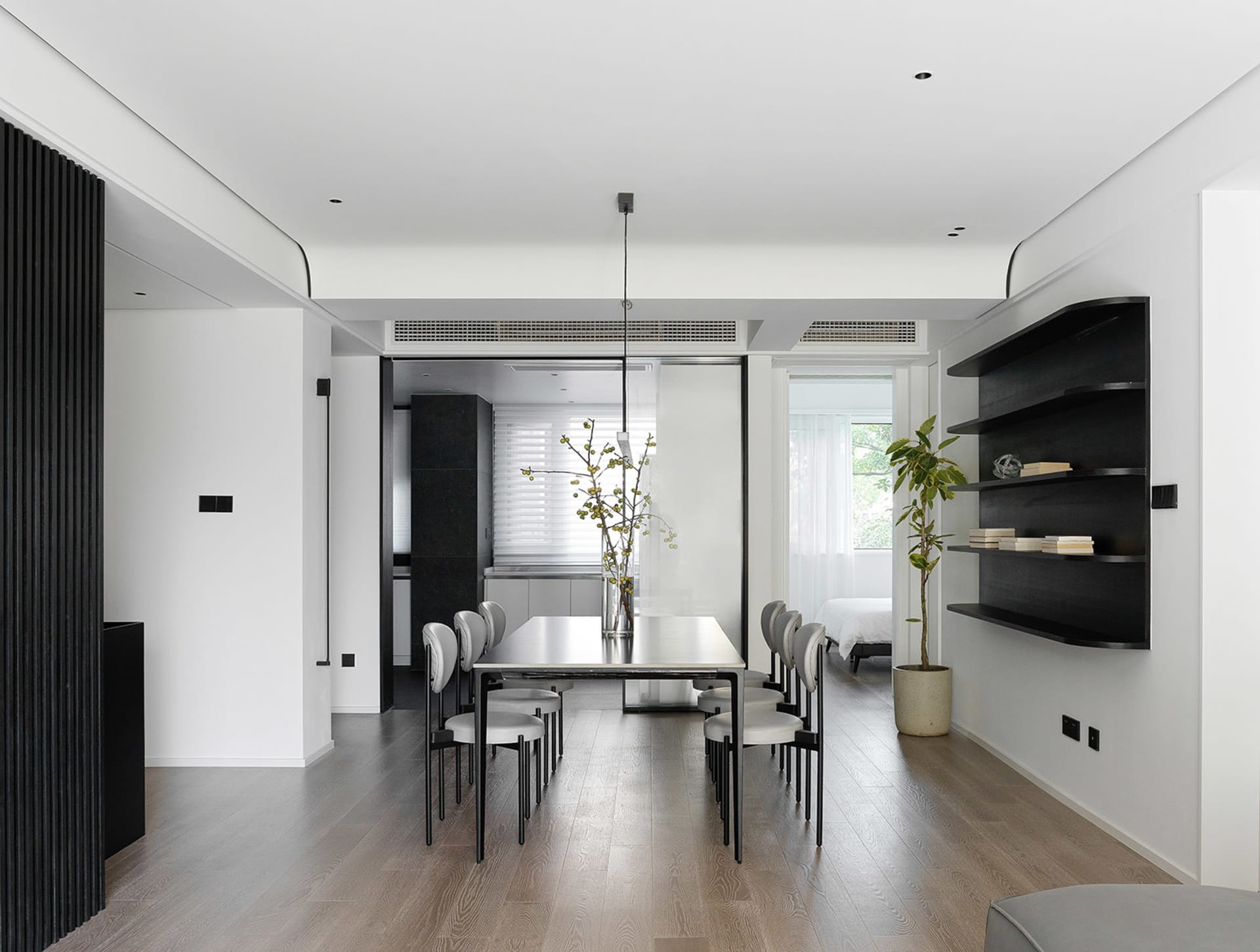 Modern minimalist living room with a wooden floor, white walls, and simple furniture arrangement.