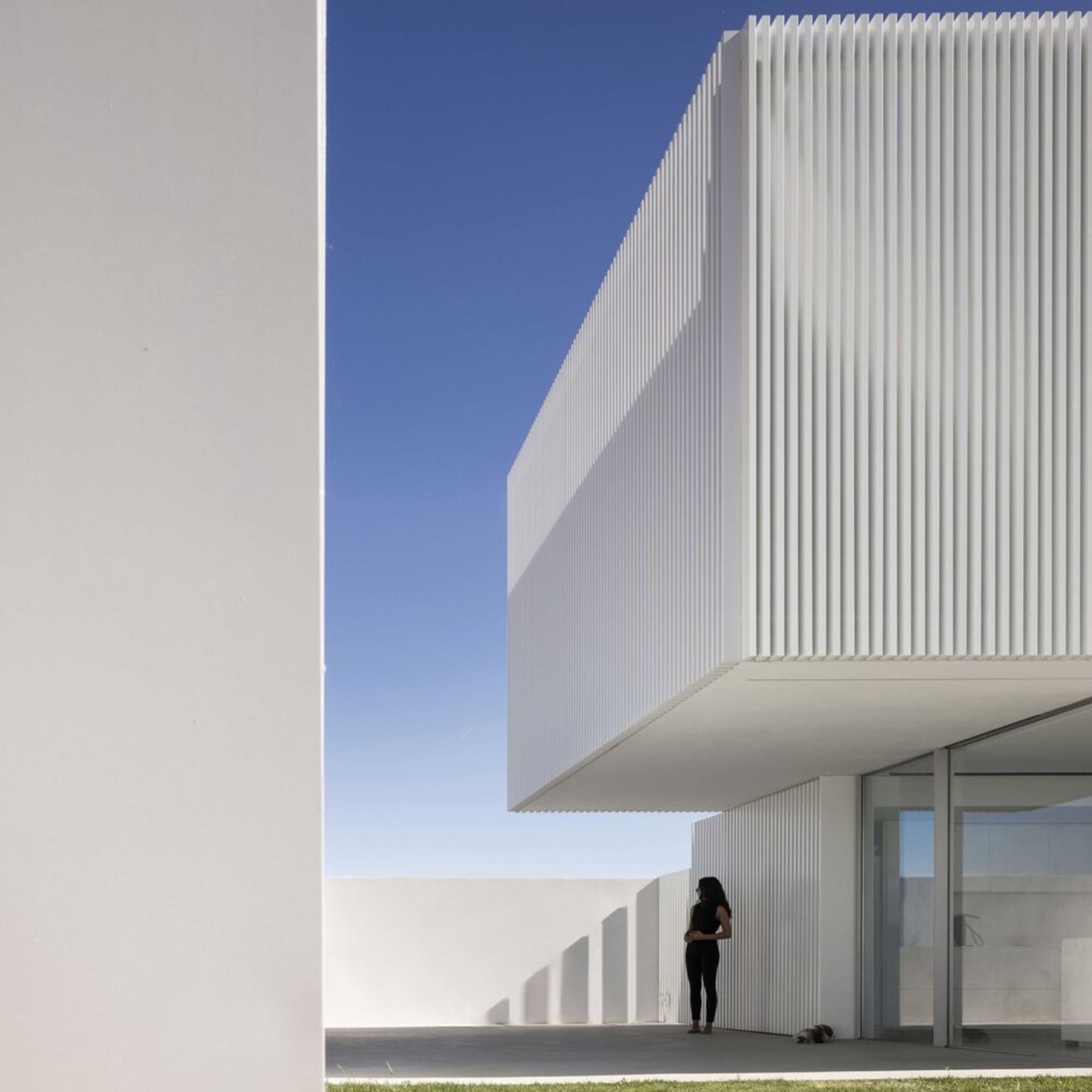 A minimalist white building exterior with clean lines and a sliding door.