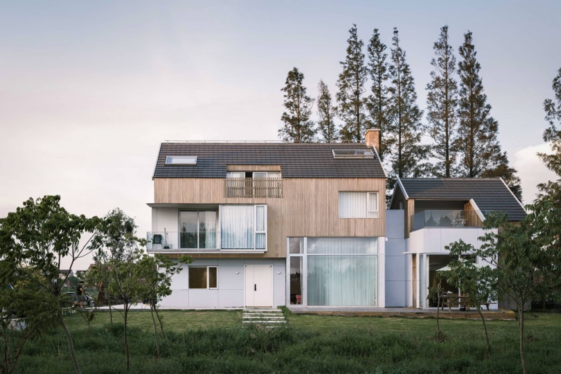 A modern residential home with a dock and pool, featuring wooden exterior, glass windows, and concrete patio.