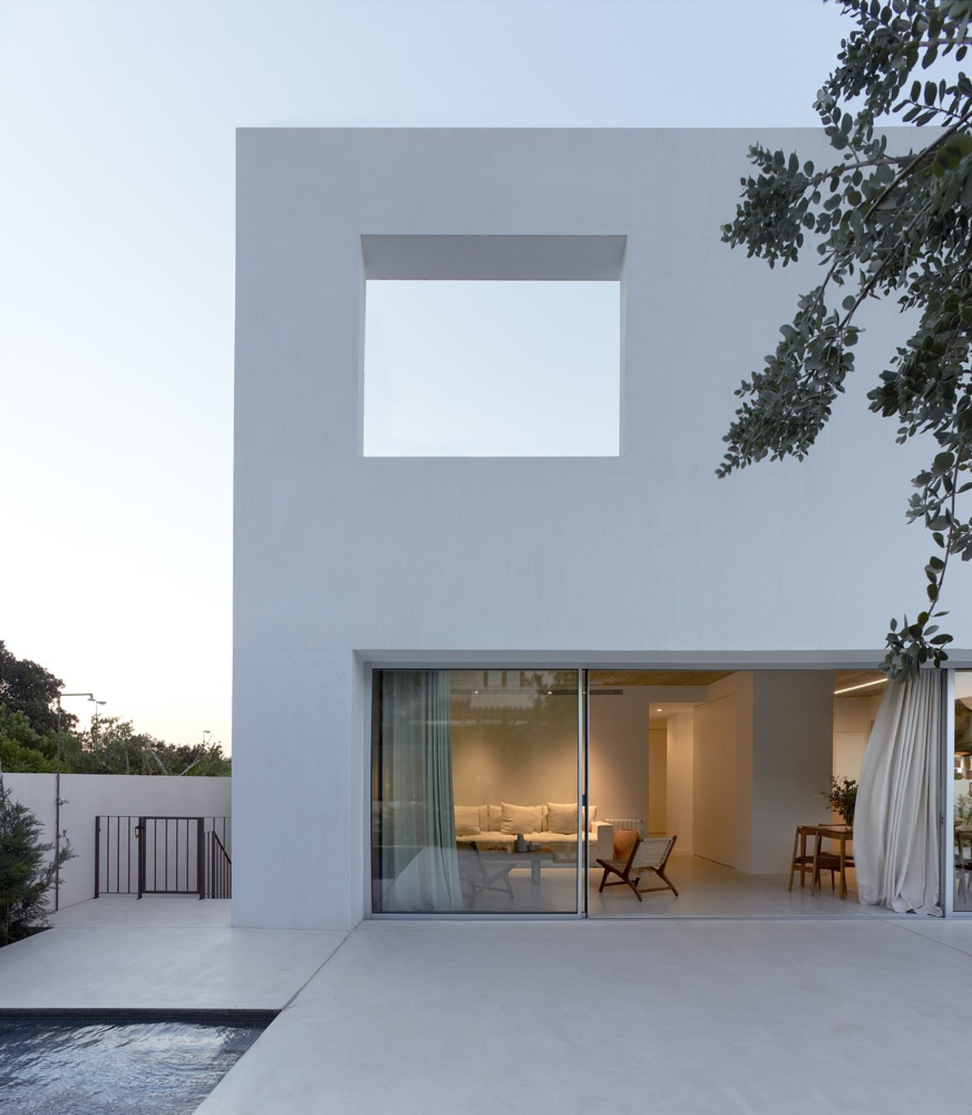Modern, minimalist house exterior with a large window and white paint.