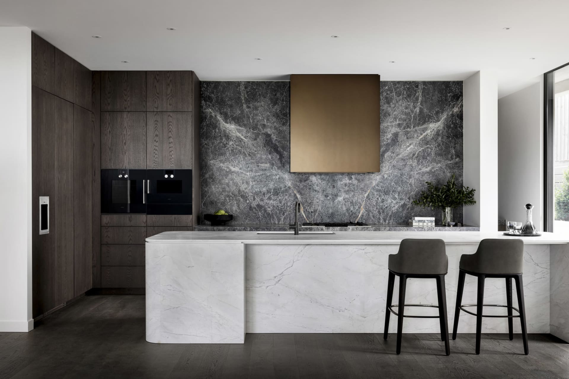 Contemporary residential kitchen featuring dark wood cabinets, a marble backsplash, and a marble kitchen island.