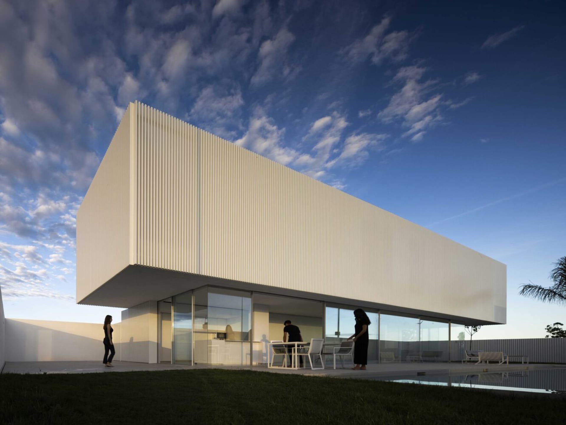 Modern house with white metal cladding and large glass windows.