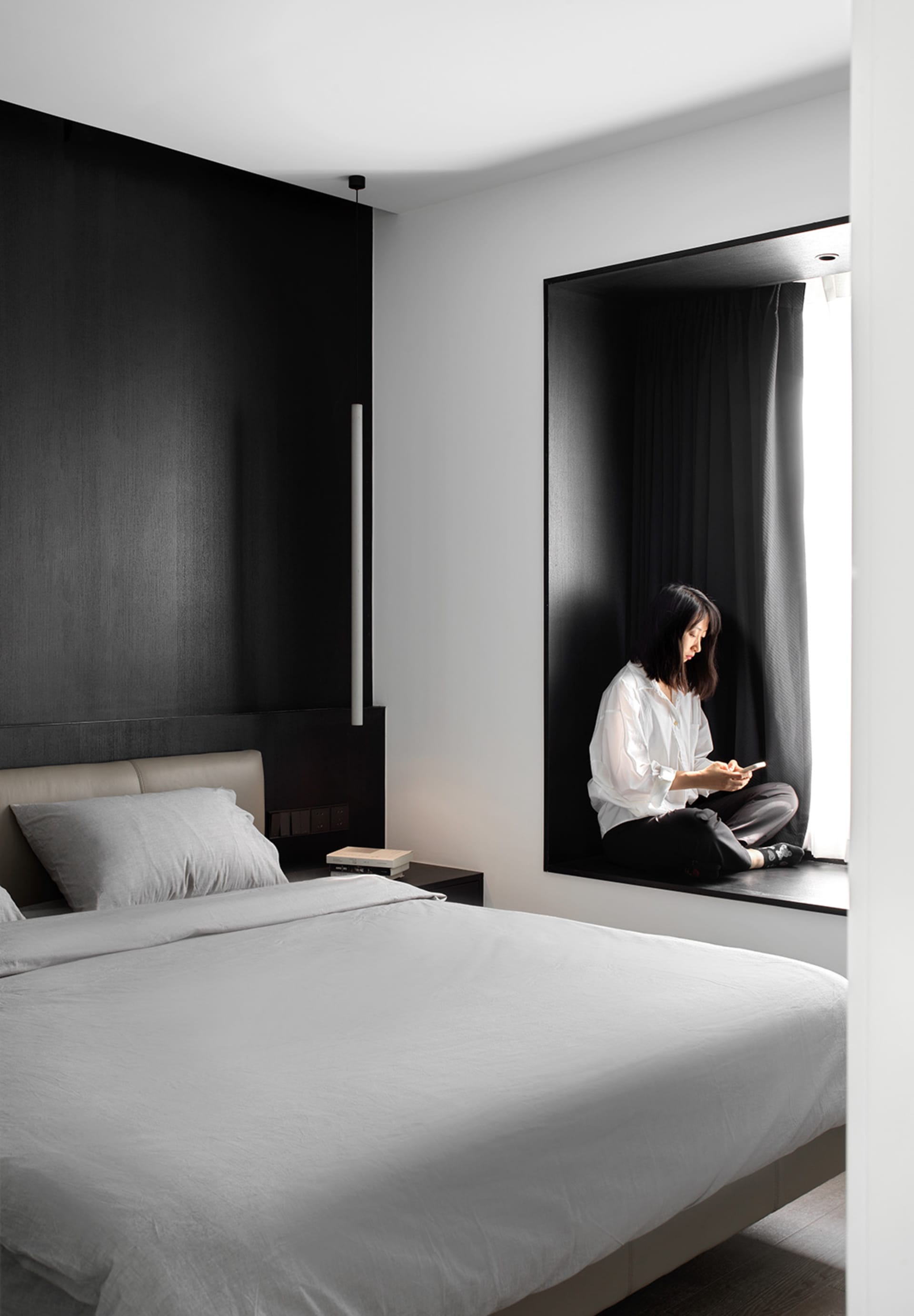 A modern minimalist bedroom with a large bed featuring soft textiles and a dark wood headboard.