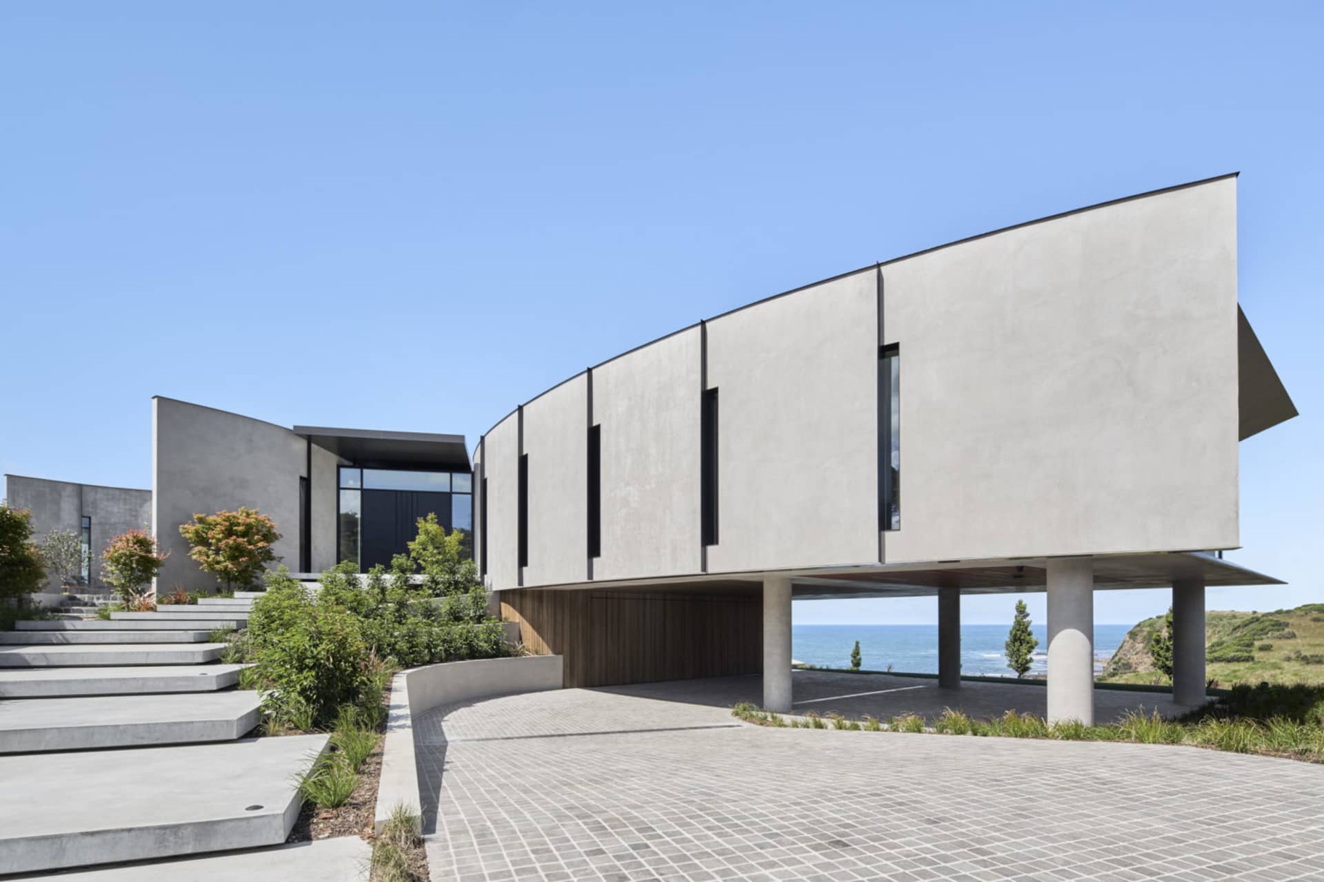 A modern residential building with concrete exterior and large glass windows.