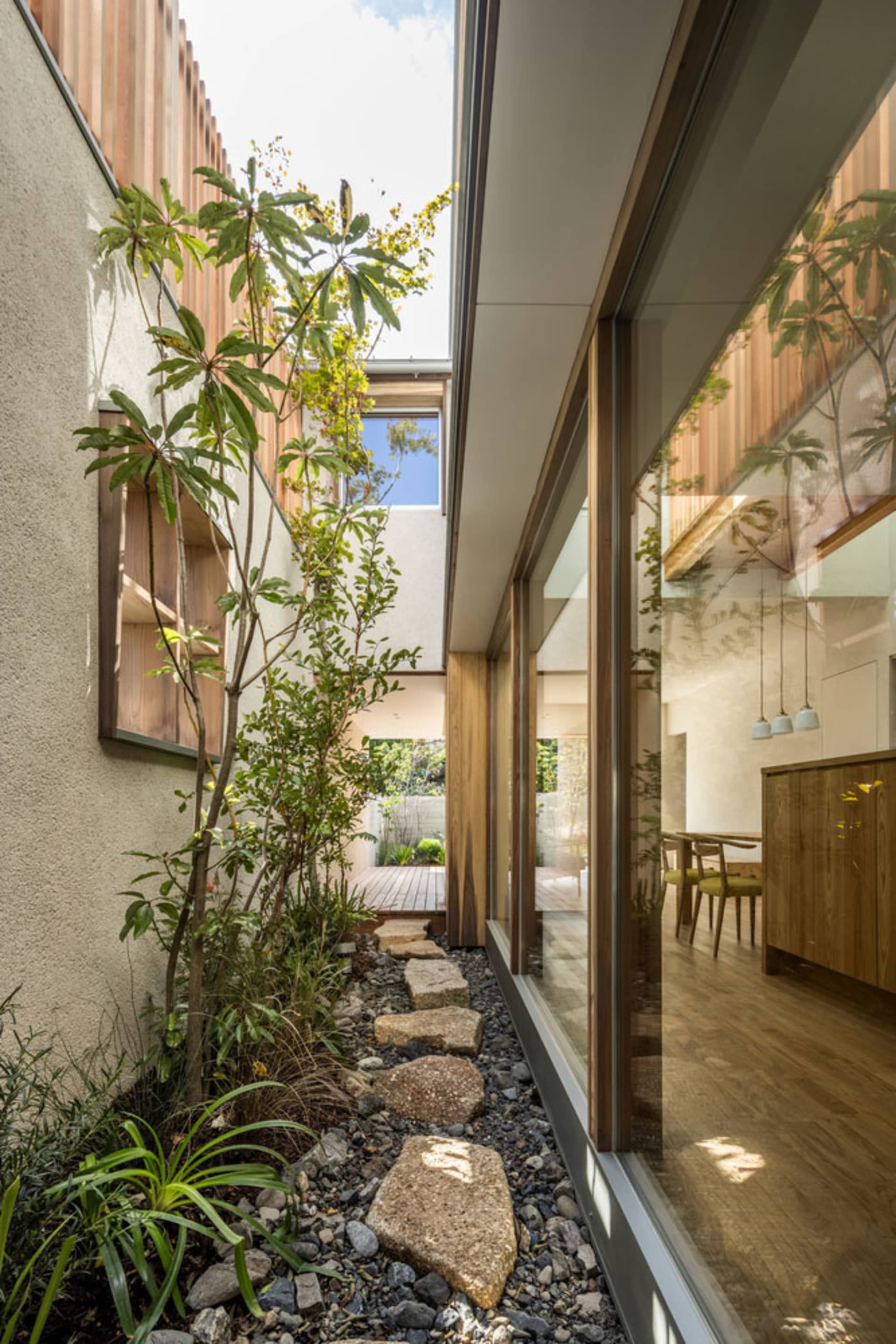 現代住宅花園，搭配木質牆面、石板步道與綠意植栽。