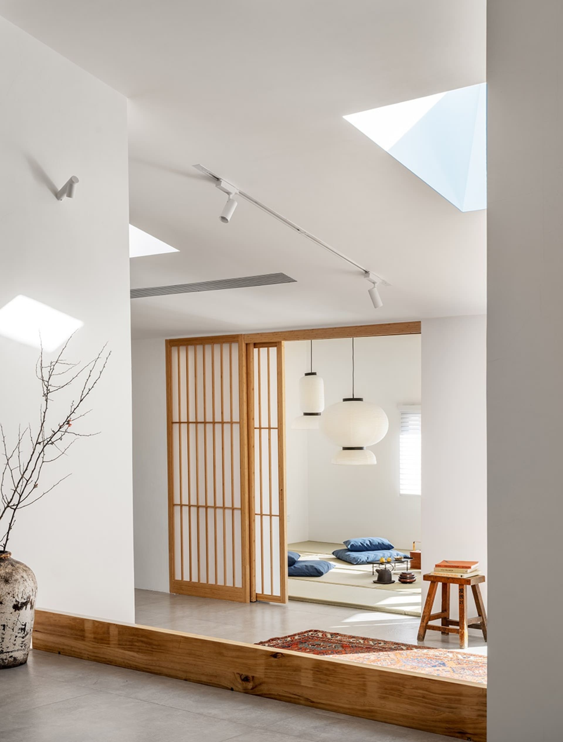 A minimalist living room with wooden elements, including a wooden floor, wooden furniture, and a wooden screen.