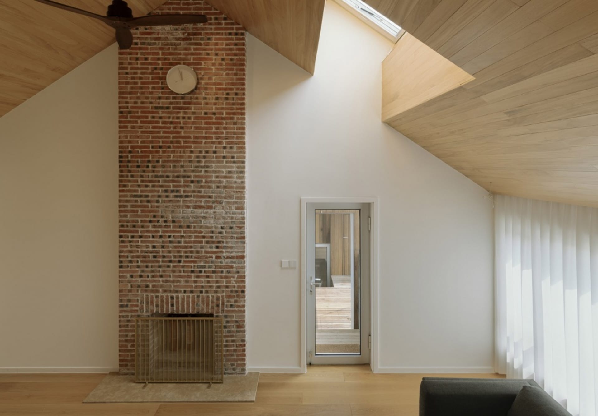 Modern living room featuring brick and wooden walls, glass door, and a cozy fireplace.