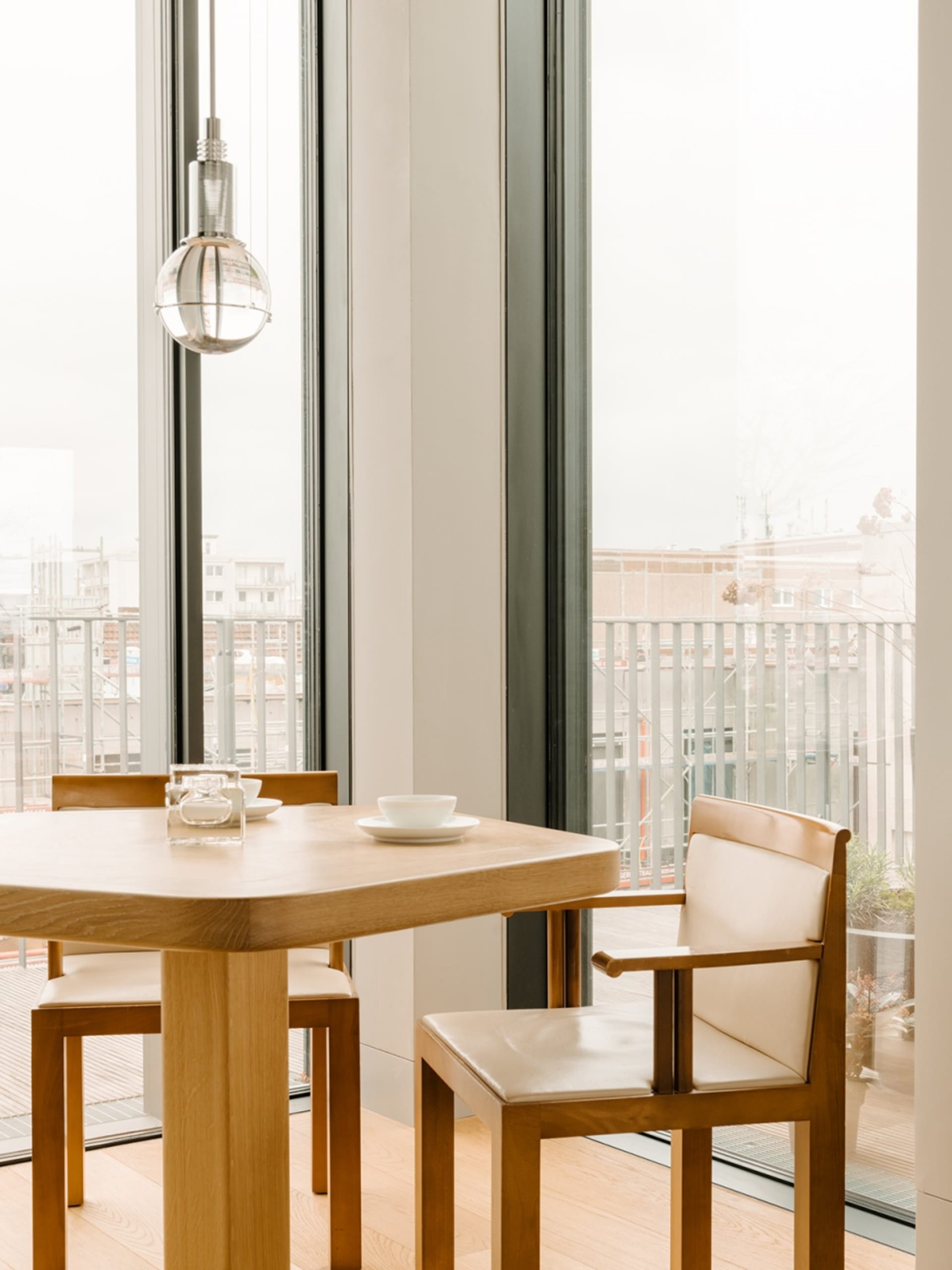 Modern dining room with wooden table, glass windows, and minimalist design.