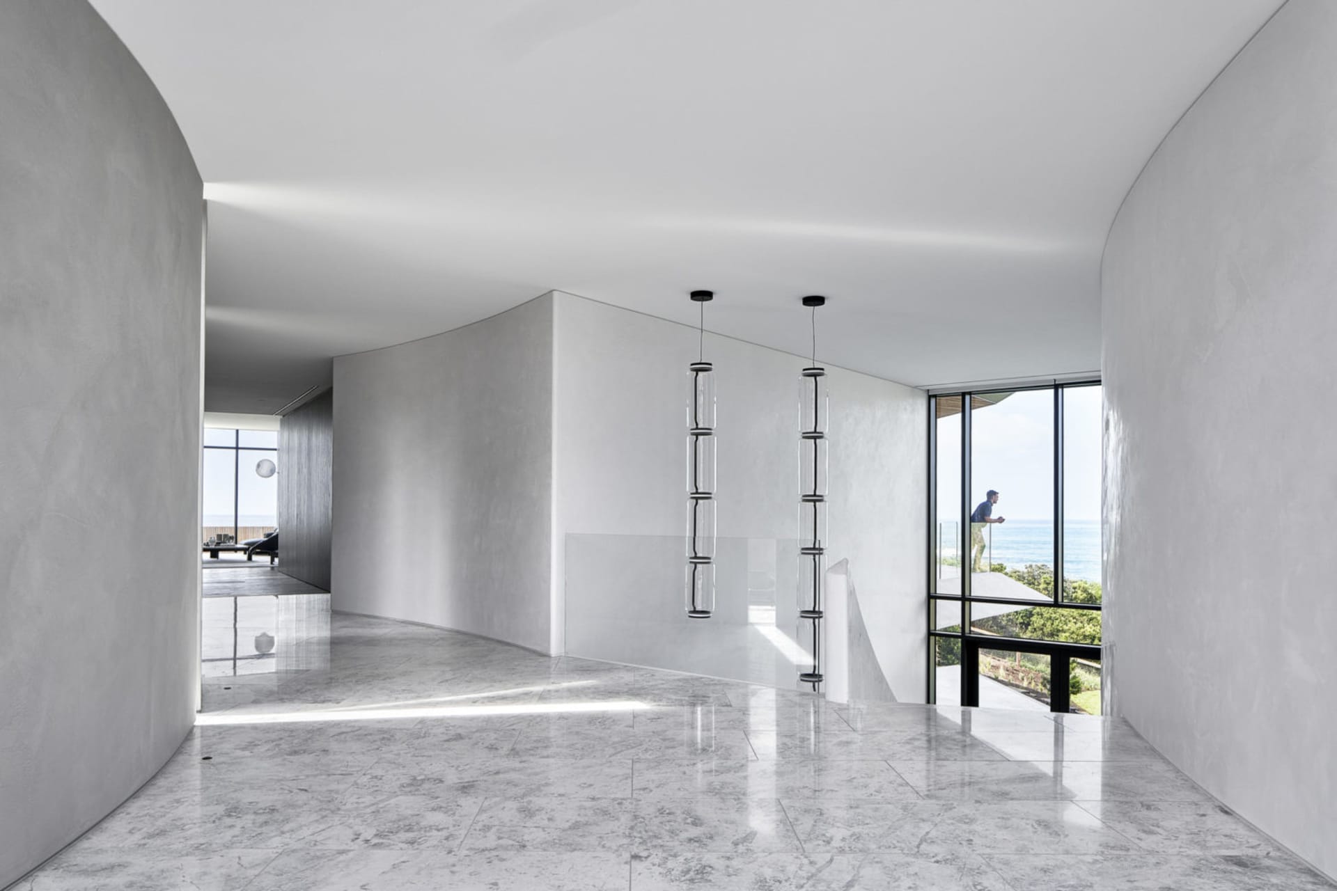 A minimalist residential interior with marble flooring, glass walls, and concrete accents.