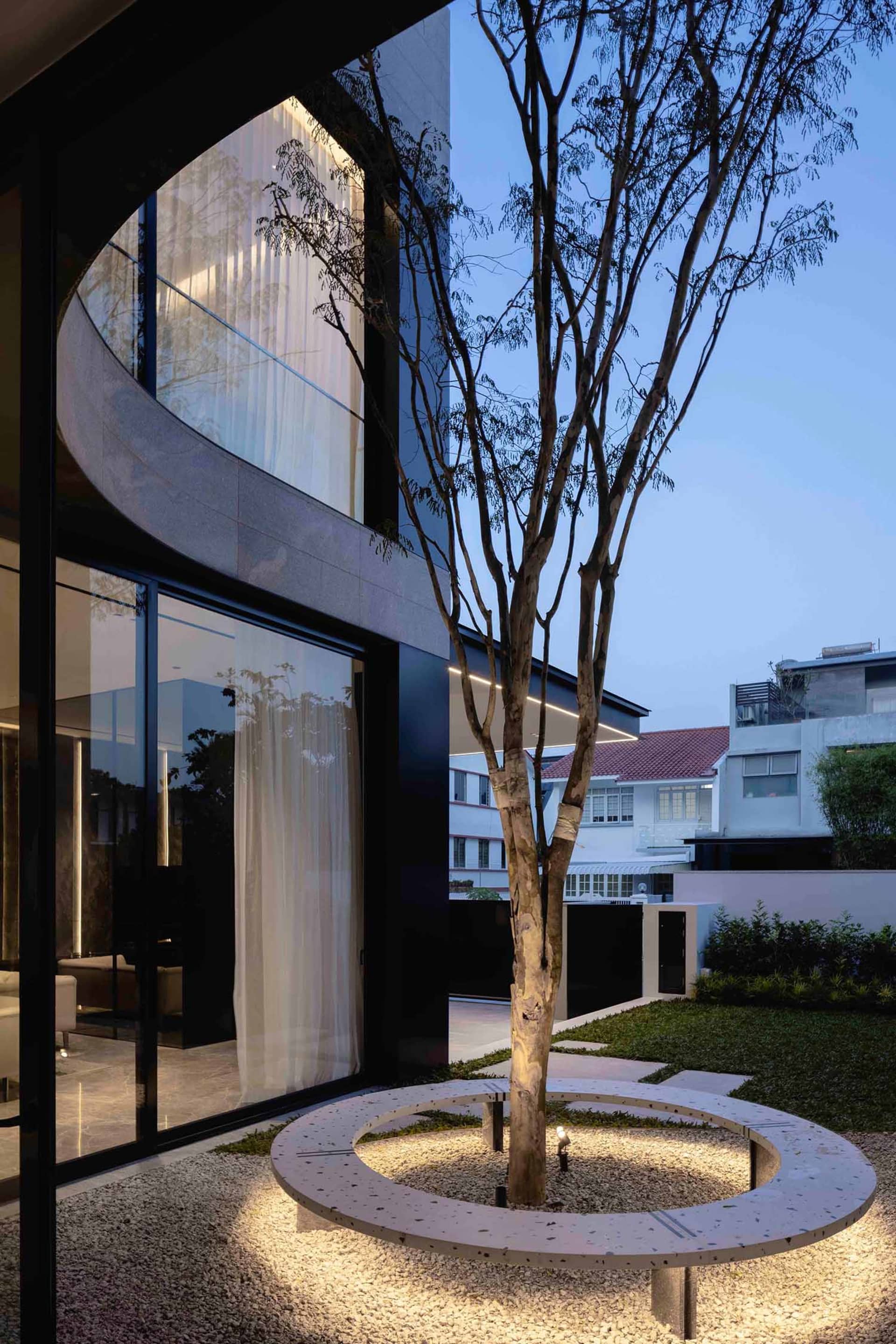 Modern minimalist patio area with terrazzo flooring and a single tree at the center.