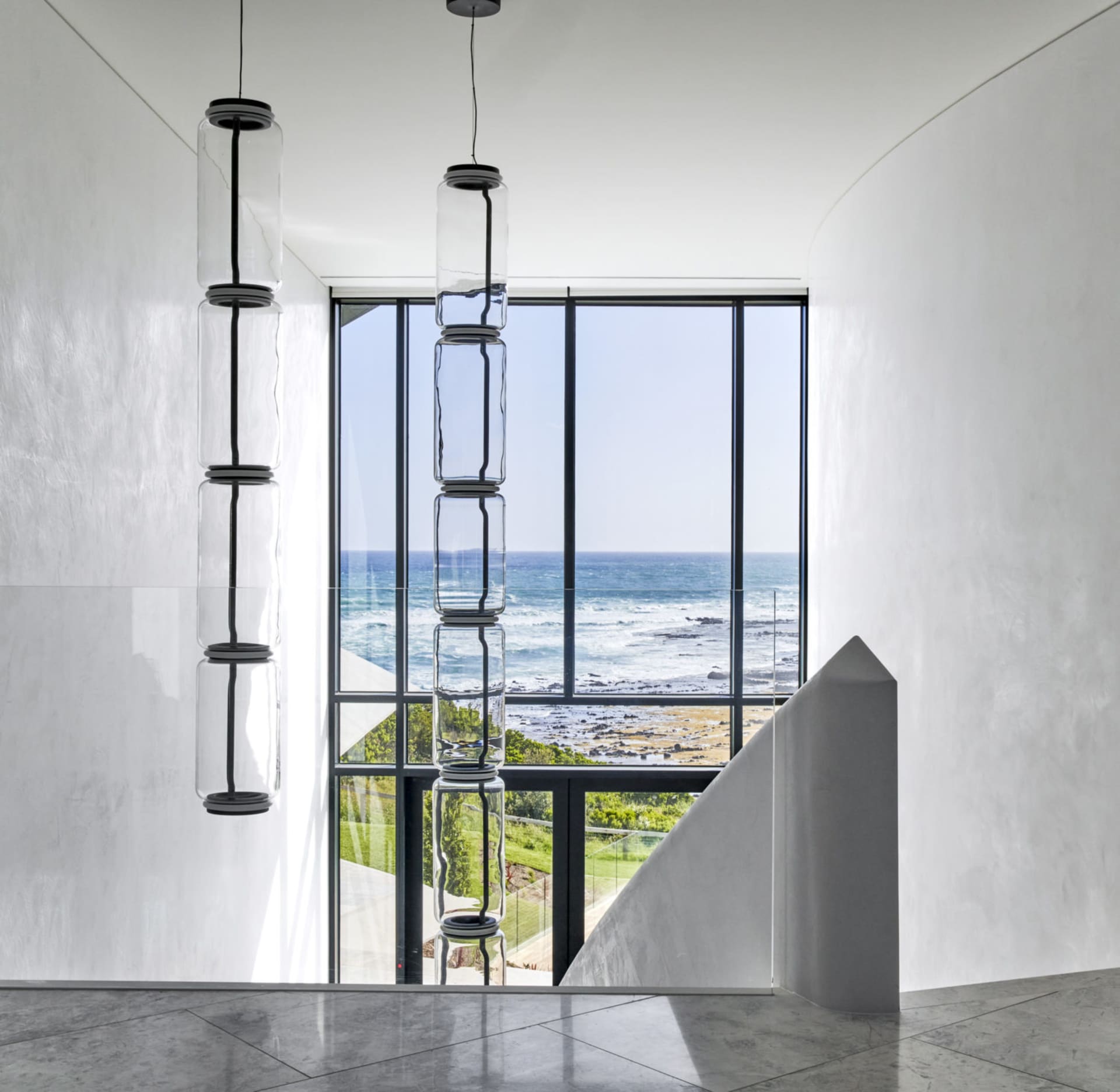 Modern residential interior with large glass window showcasing coastal view