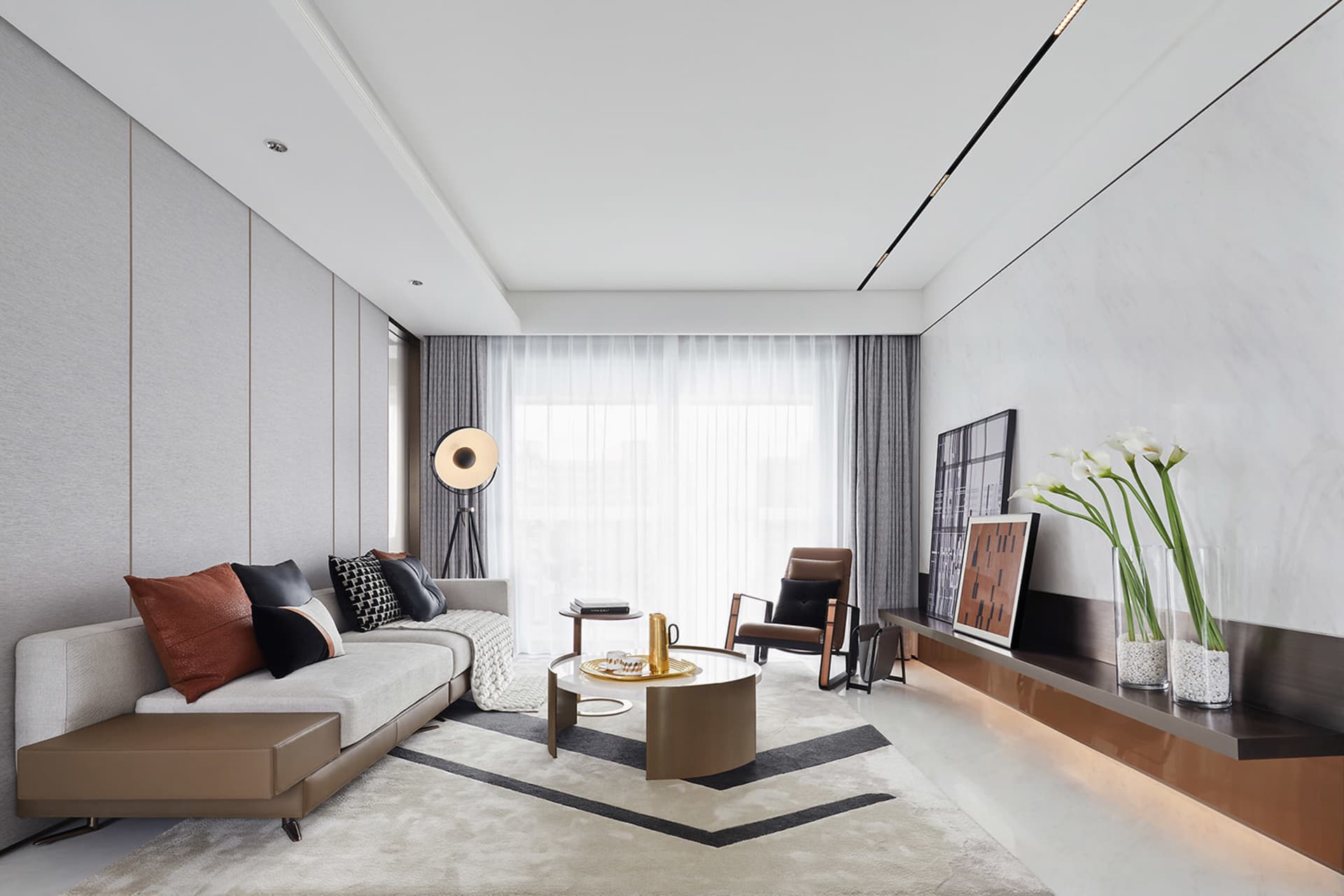 A modern living room featuring fabric seating, glass coffee table, and metal accents.