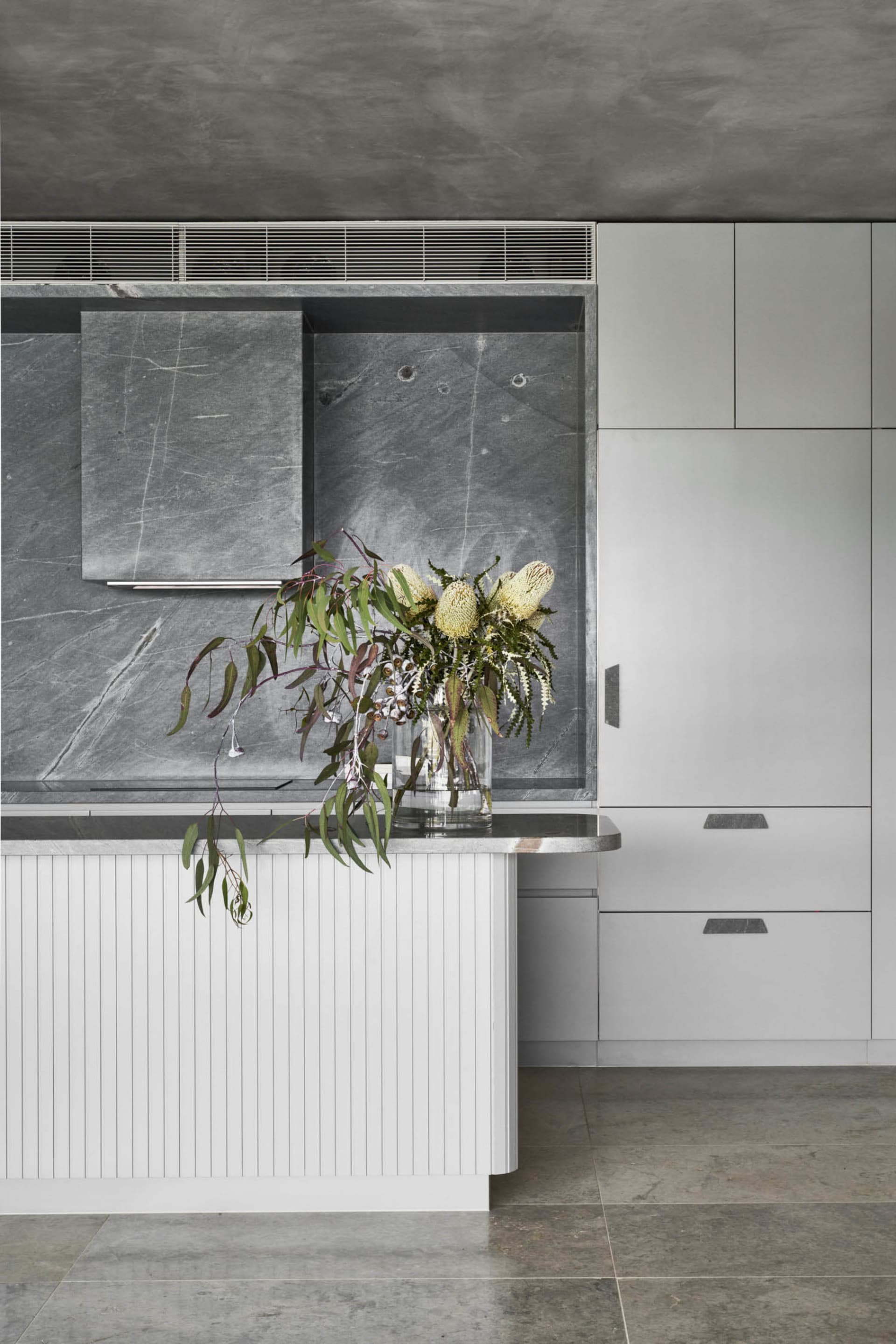 A minimalist kitchen featuring natural stone counter tops and a marble backsplash.