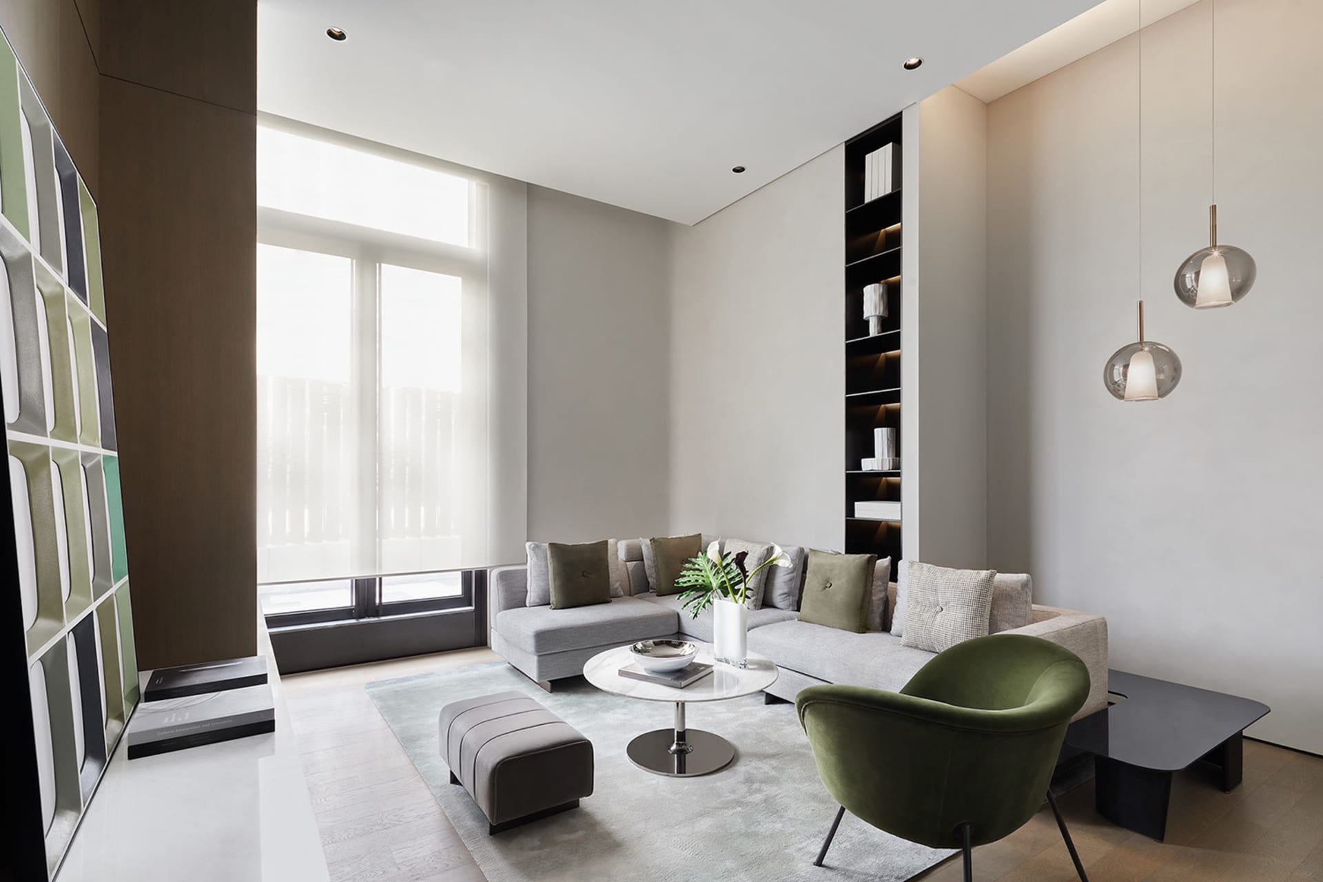 Modern minimalist living room with grey sectional sofa, round coffee table, green chair, and large windows.