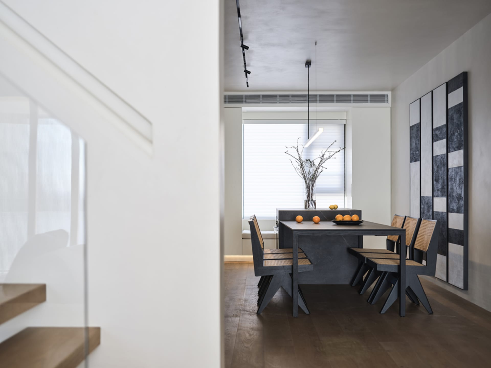 A modern industrial dining room with minimalist design, featuring a concrete dining table, wooden chairs, and a minimalist pe