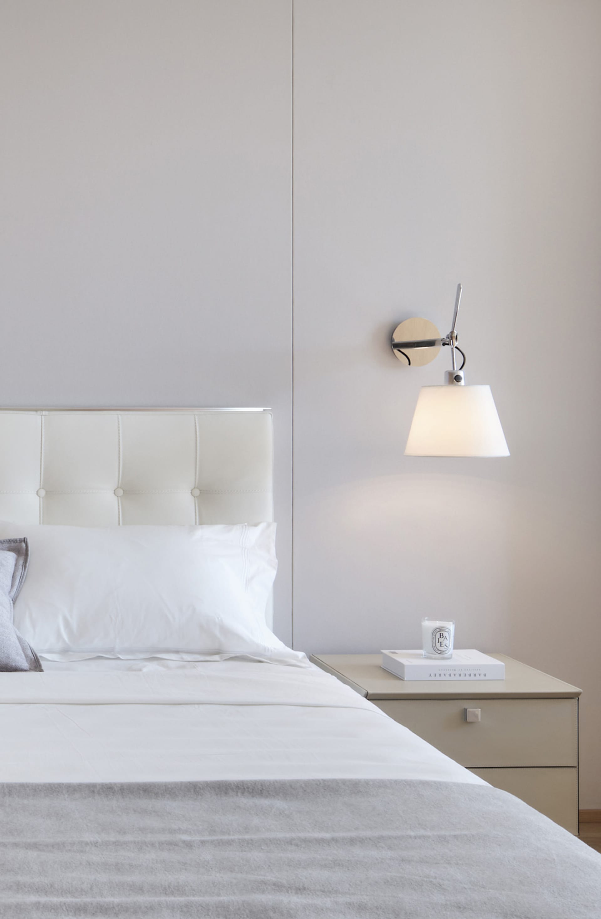 A minimalist bedroom with a white upholstered bed