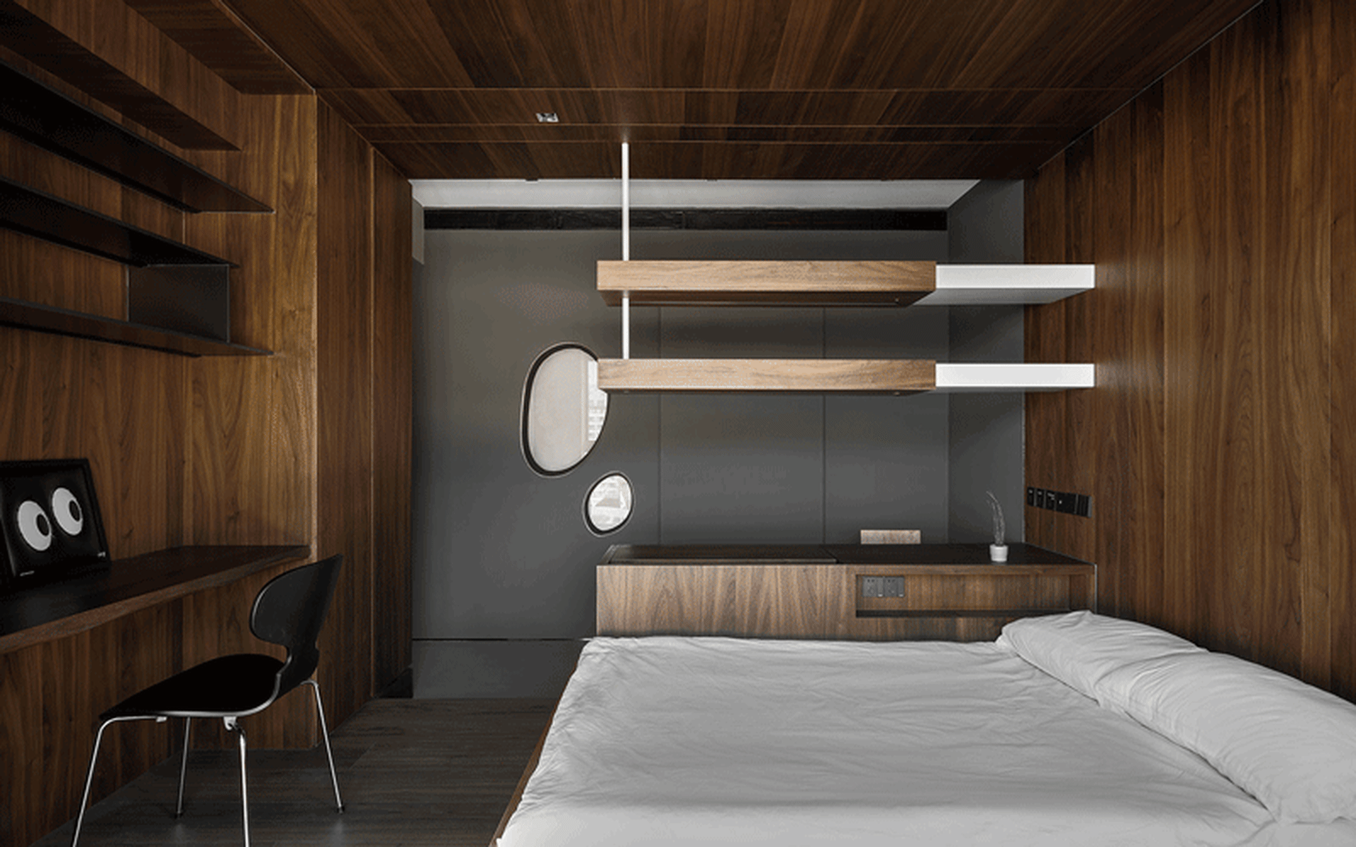 Modern minimalist bedroom featuring a bed with white sheets, floating shelves, and wooden walls and floor.