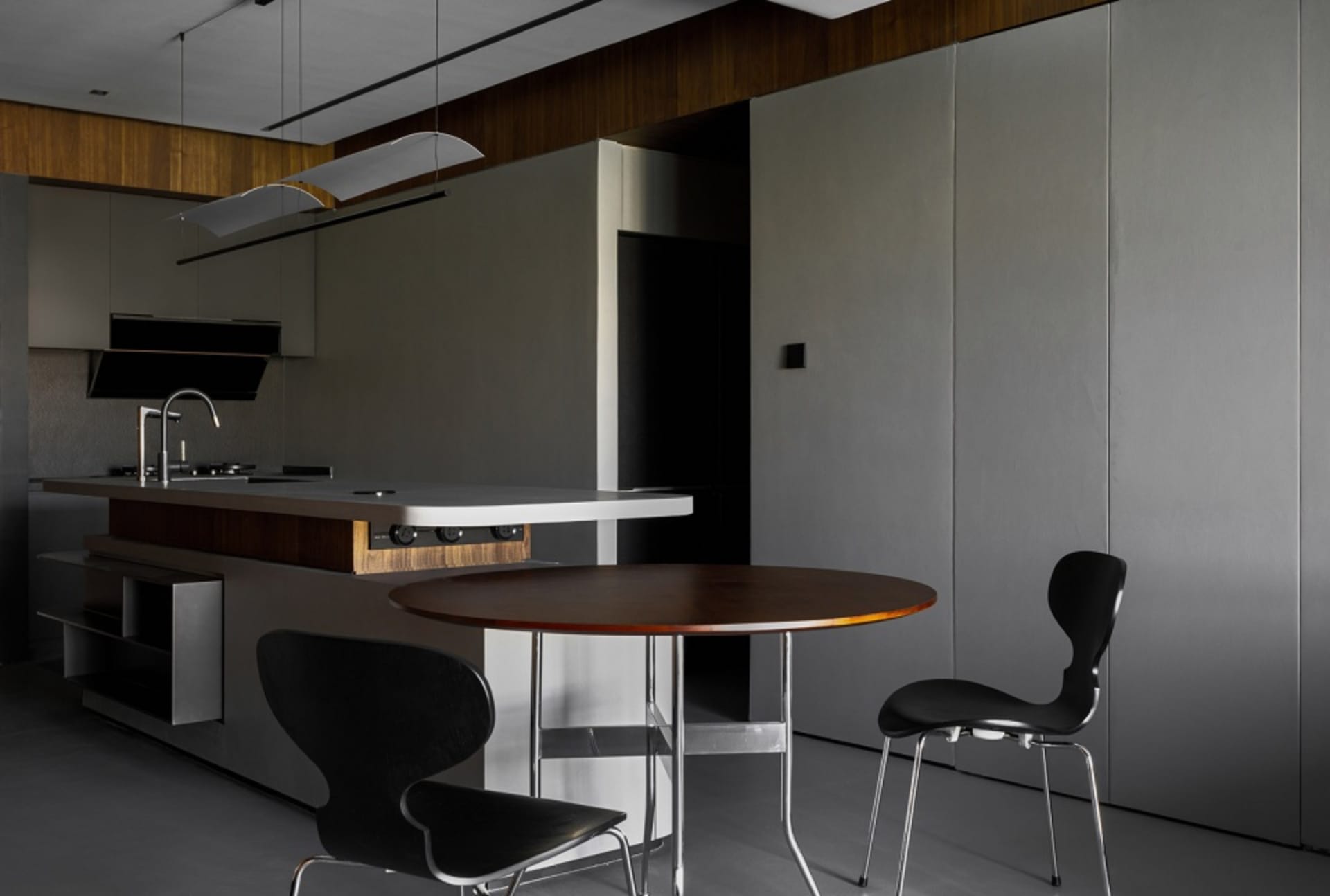 Modern kitchen with minimalist design, featuring a wooden table, black chairs, and a wood-and-metal kitchen island.