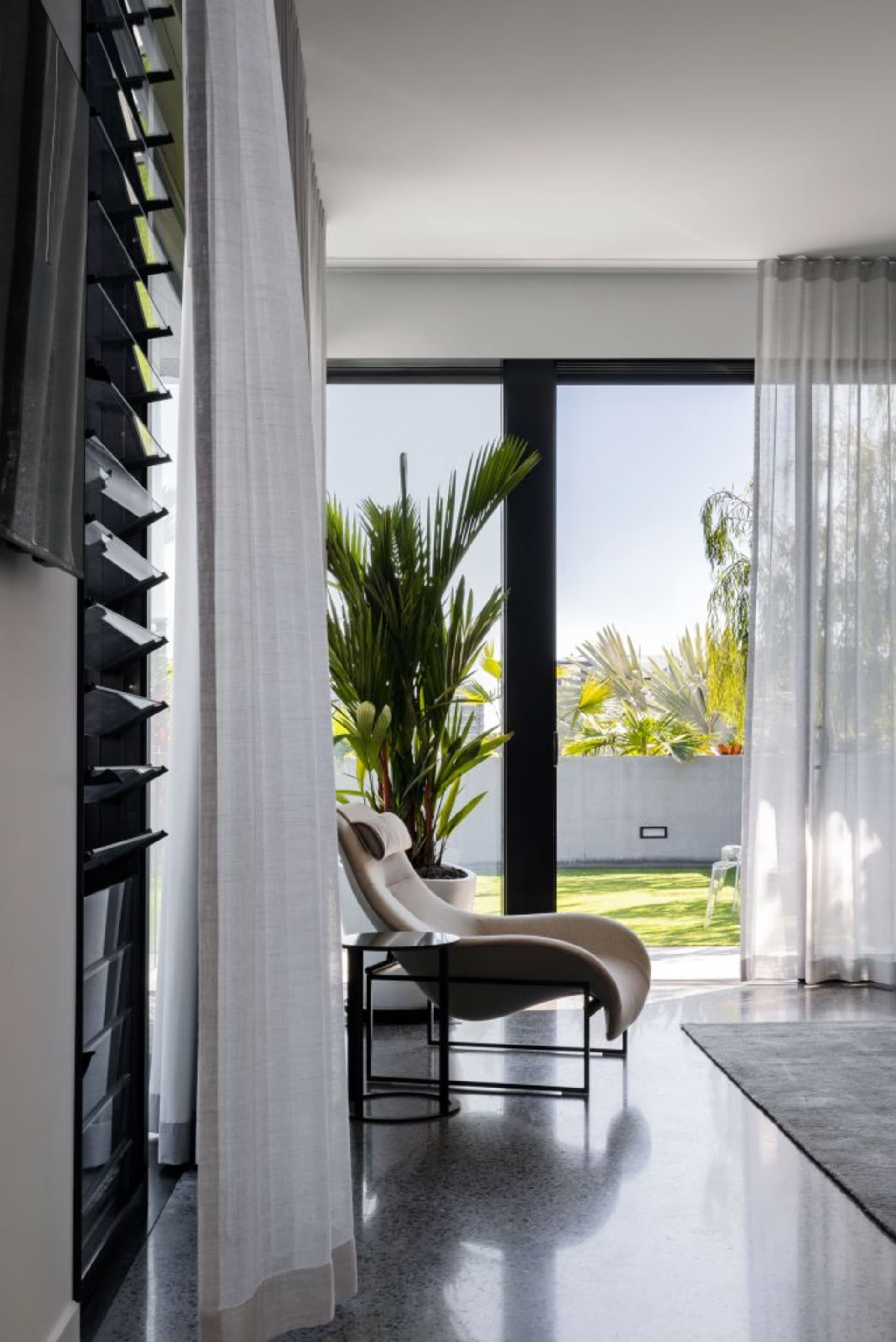A modern living room featuring glass curtains and concrete furniture, providing a sleek and contemporary aesthetic.