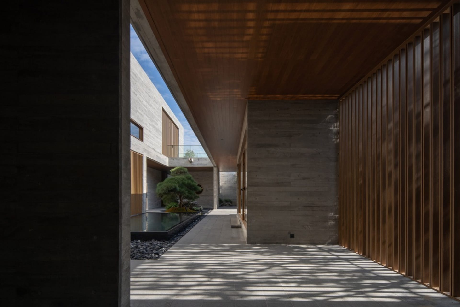 A minimalist design featuring a courtyard with concrete walls and wooden paneling.