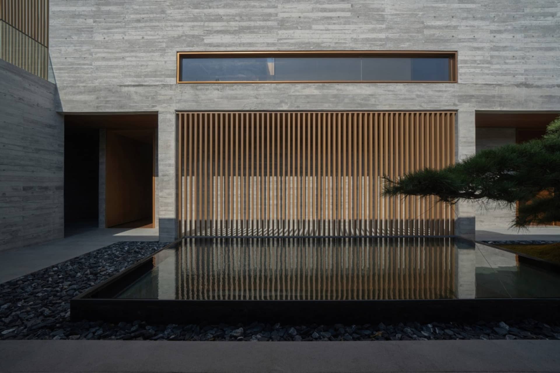 A modern outdoor space featuring concrete walls, wooden slats, and a water feature.