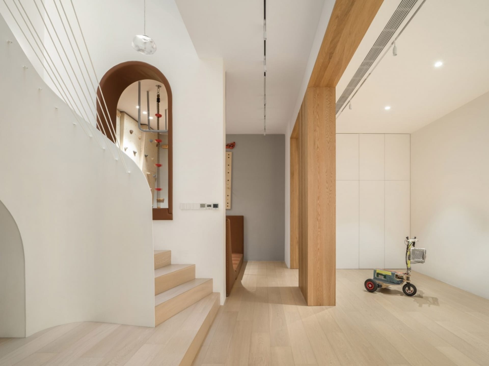 A modern residential interior featuring a living room area with a concrete column, light-colored wood paneling, and a small c