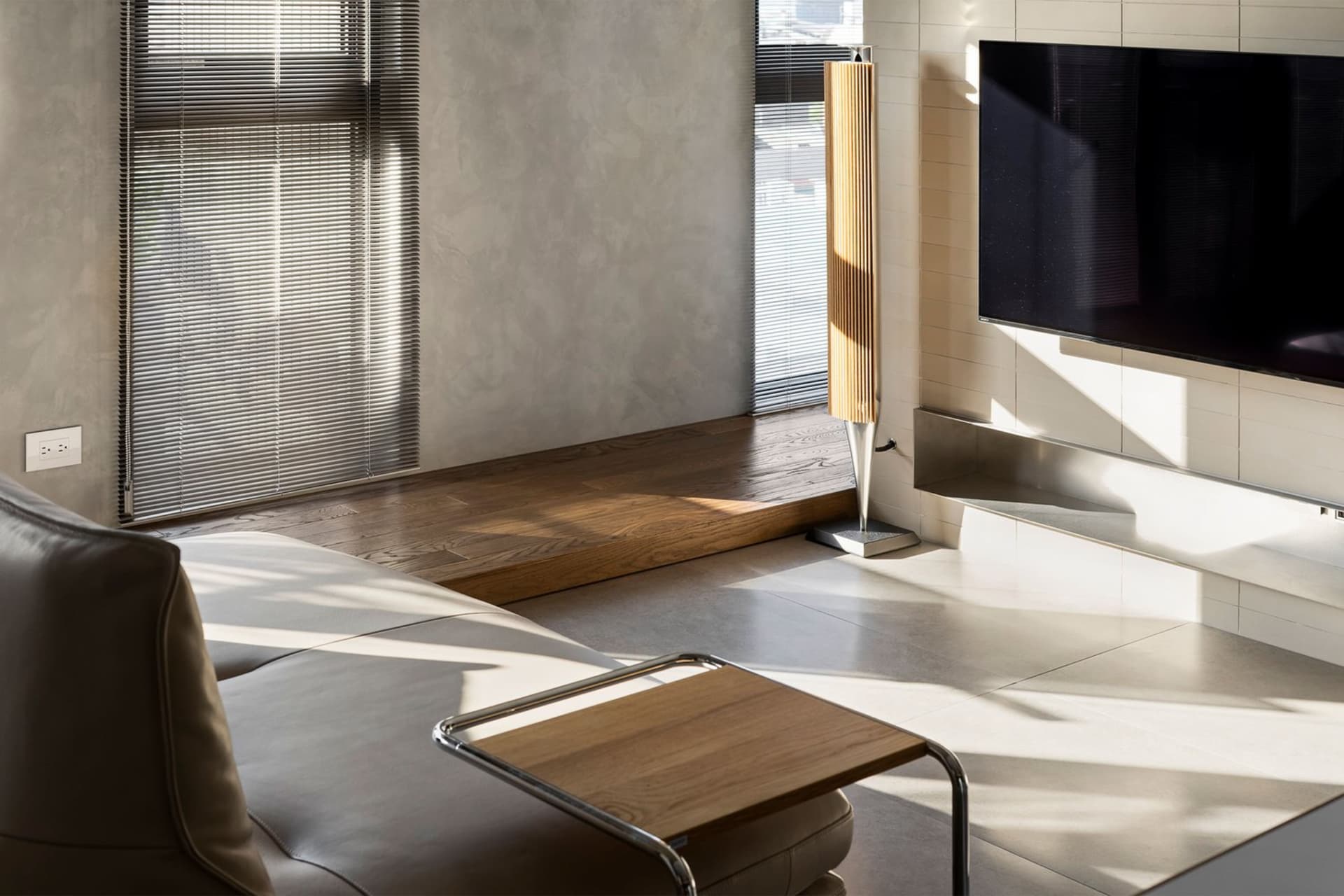 A modern living room with minimalist design featuring wood, metal, and concrete materials.