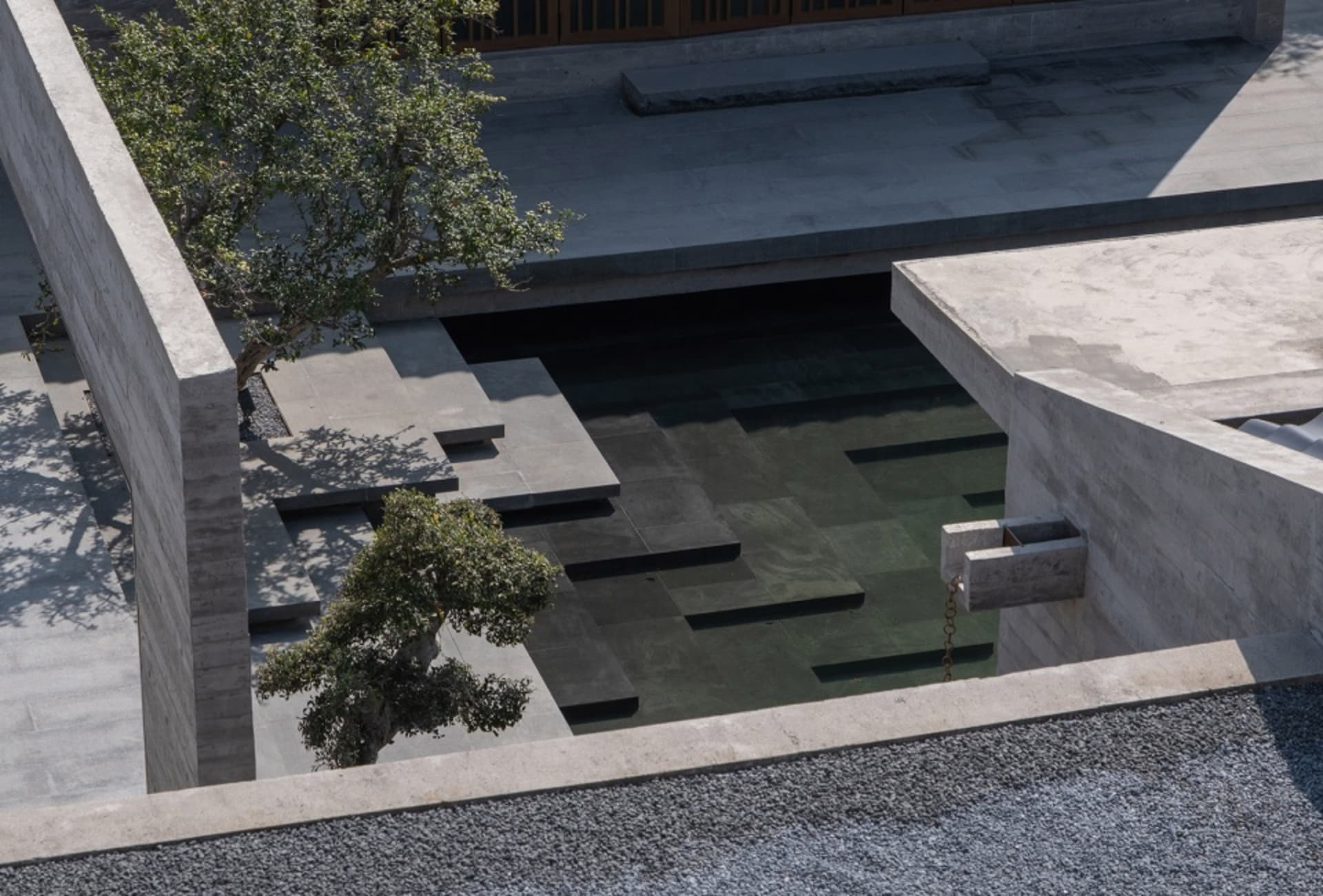 Modern outdoor space featuring a concrete and glass architectural plan with a pool and trees.