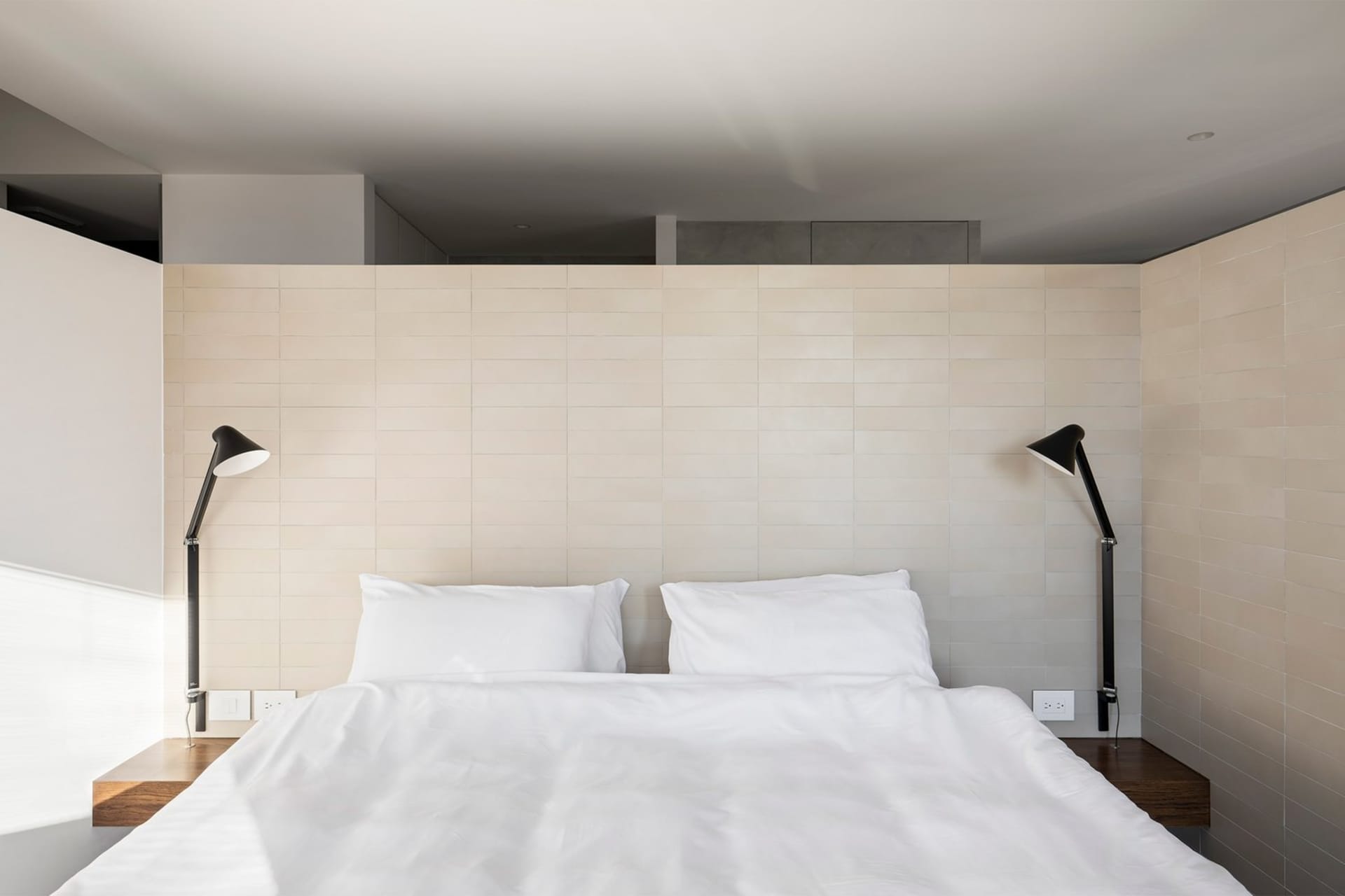 A minimalist white bedroom with modern design elements.