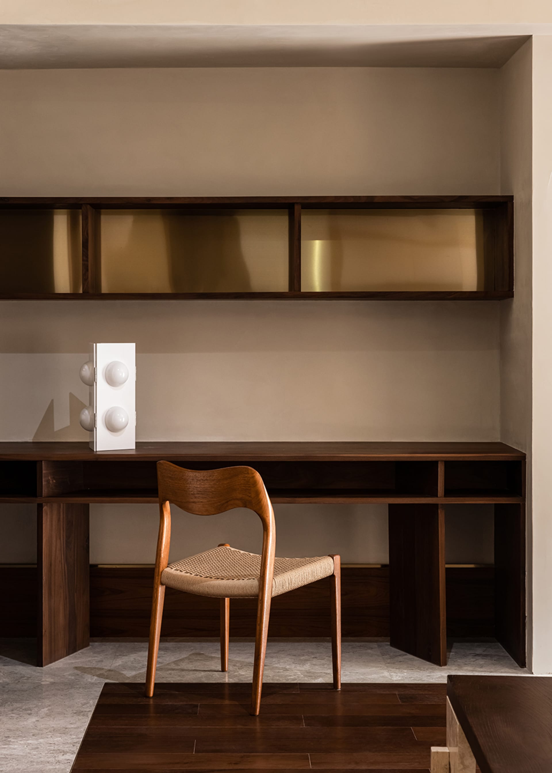 A modern home office featuring a wooden desk with a woven chair and built-in shelves.