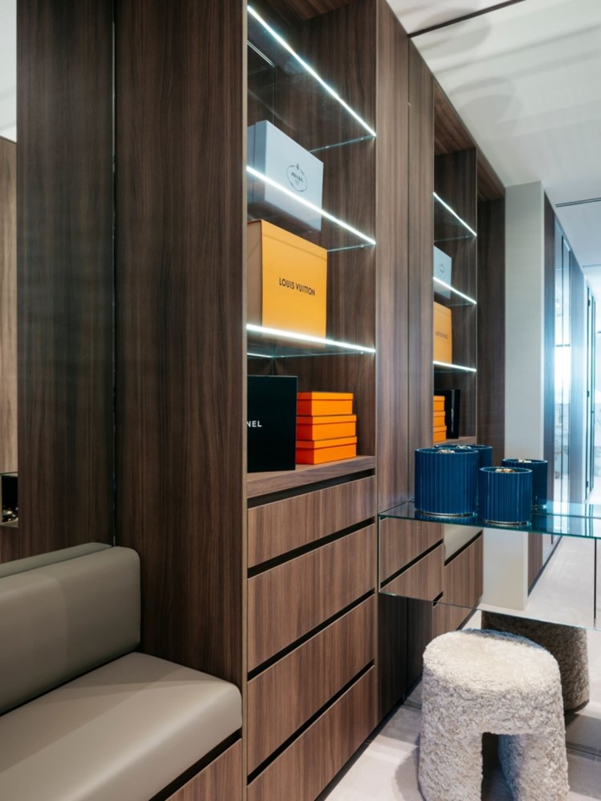 Luxurious dressing room featuring wooden cabinets and glass shelves.