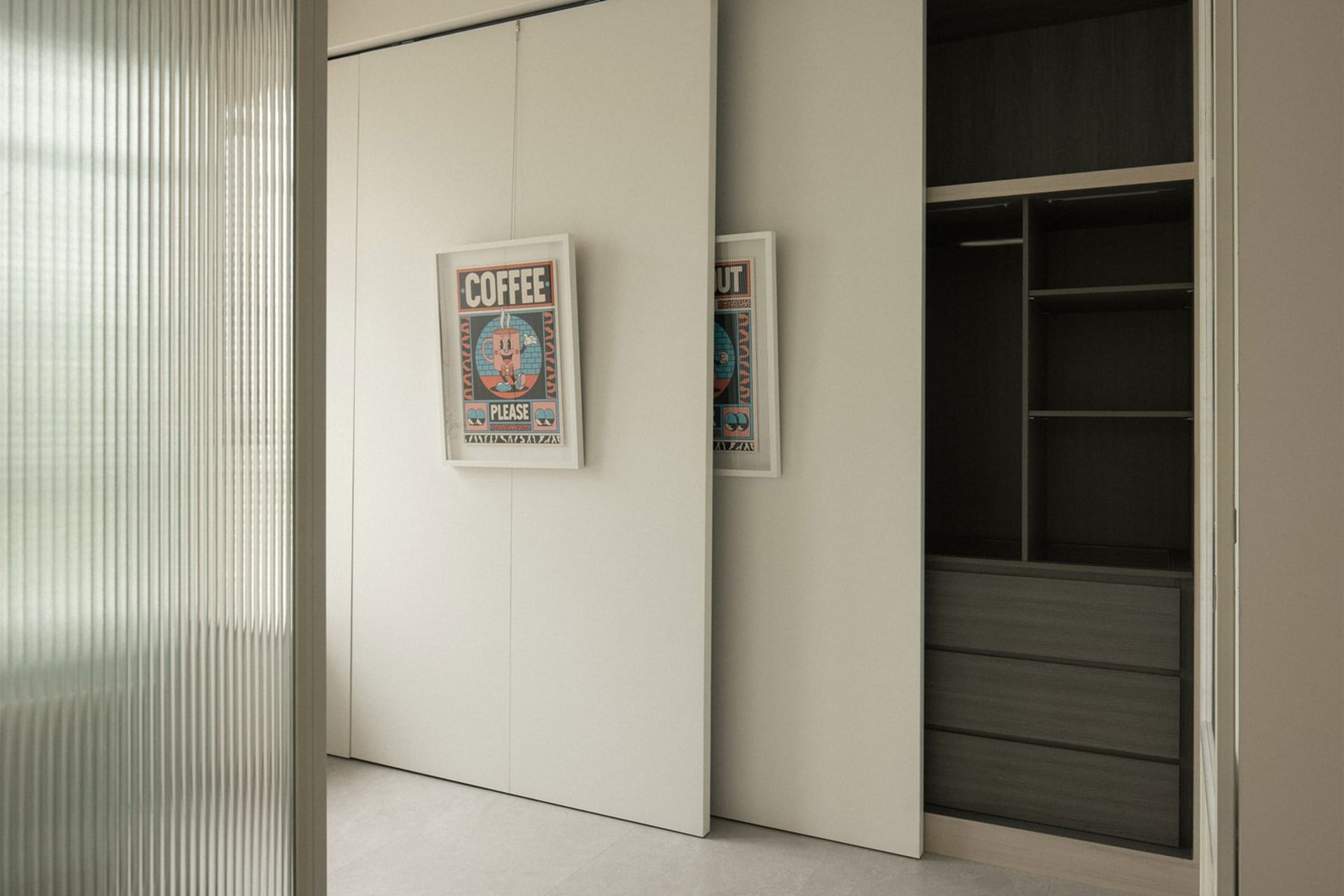 Minimalist modern closet with white sliding doors and black minimalist design, featuring framed posters.