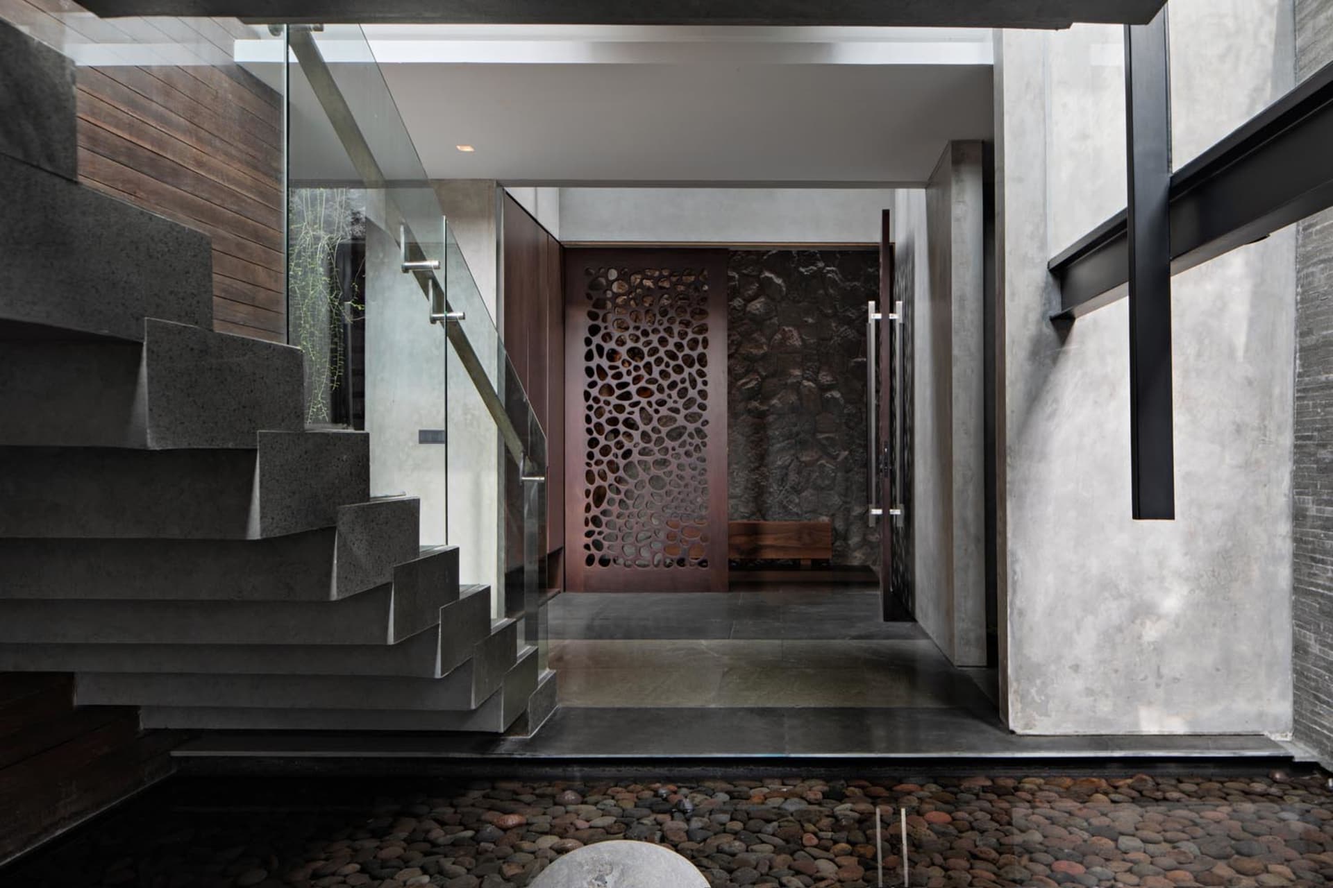 Modern entrance featuring a concrete staircase and wooden door with a stone wall in the background.