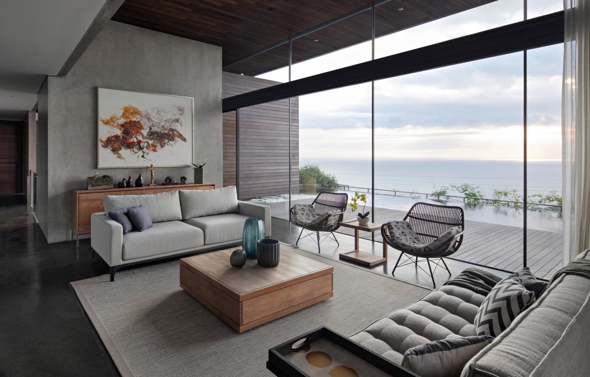 Modern living room featuring a sleek concrete floor and large windows overlooking the ocean.