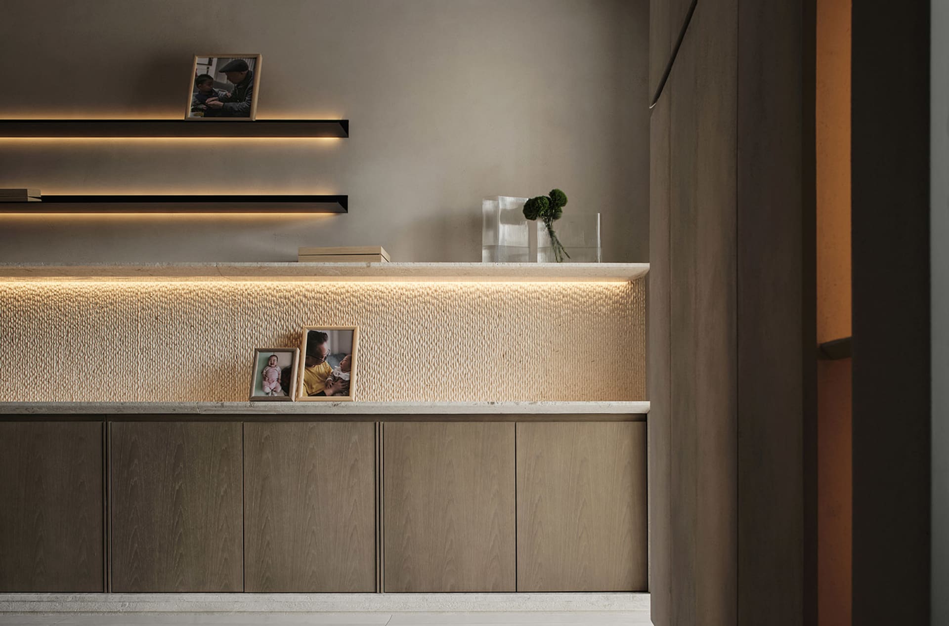 A modern minimalist wooden desk with a textured surface, illuminated by subtle lighting, featuring framed photos and greenery
