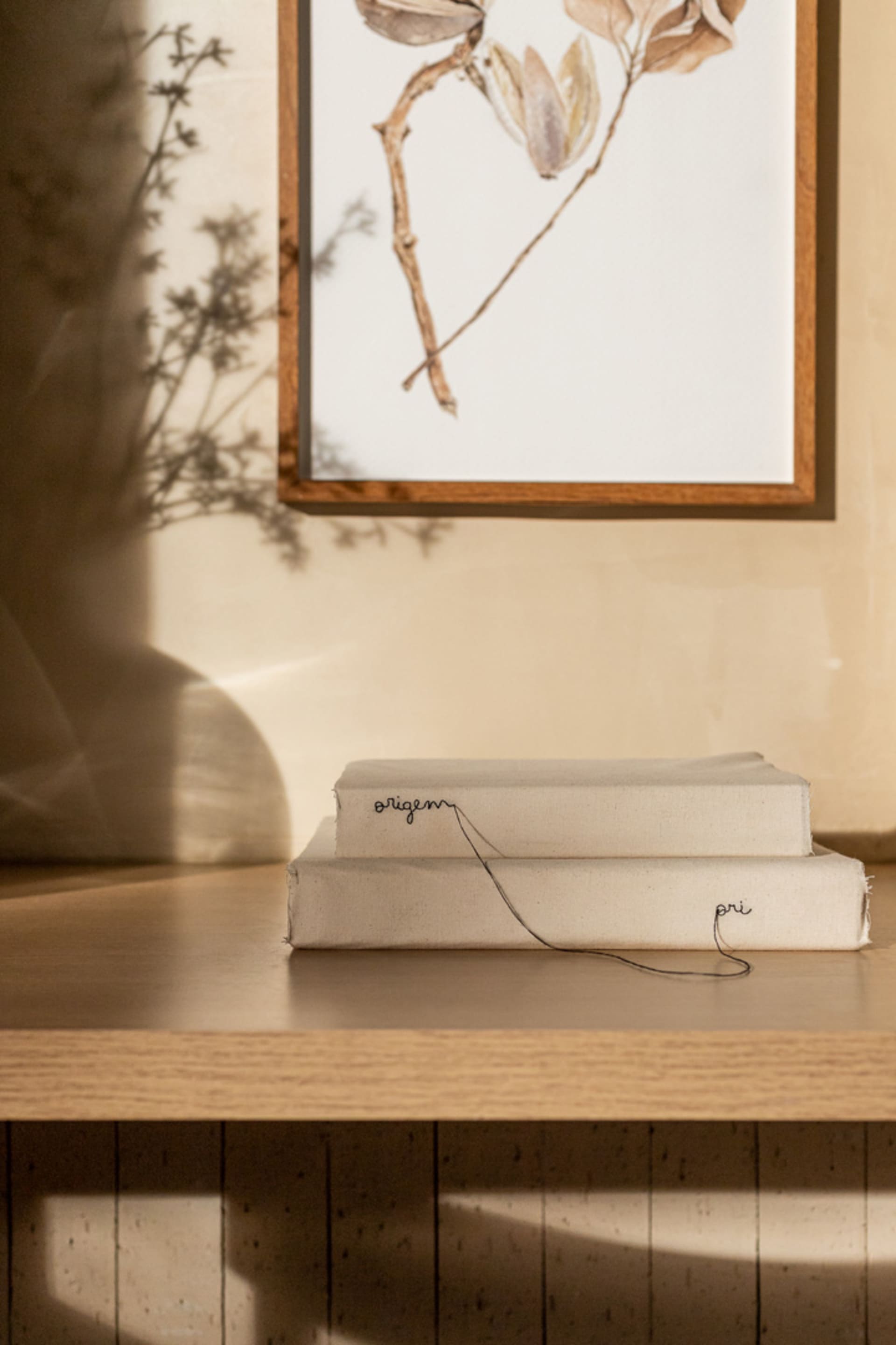 Modern shelving unit with beige canvas and wire绑带装饰,背景为浅色墙面和植物阴影。
