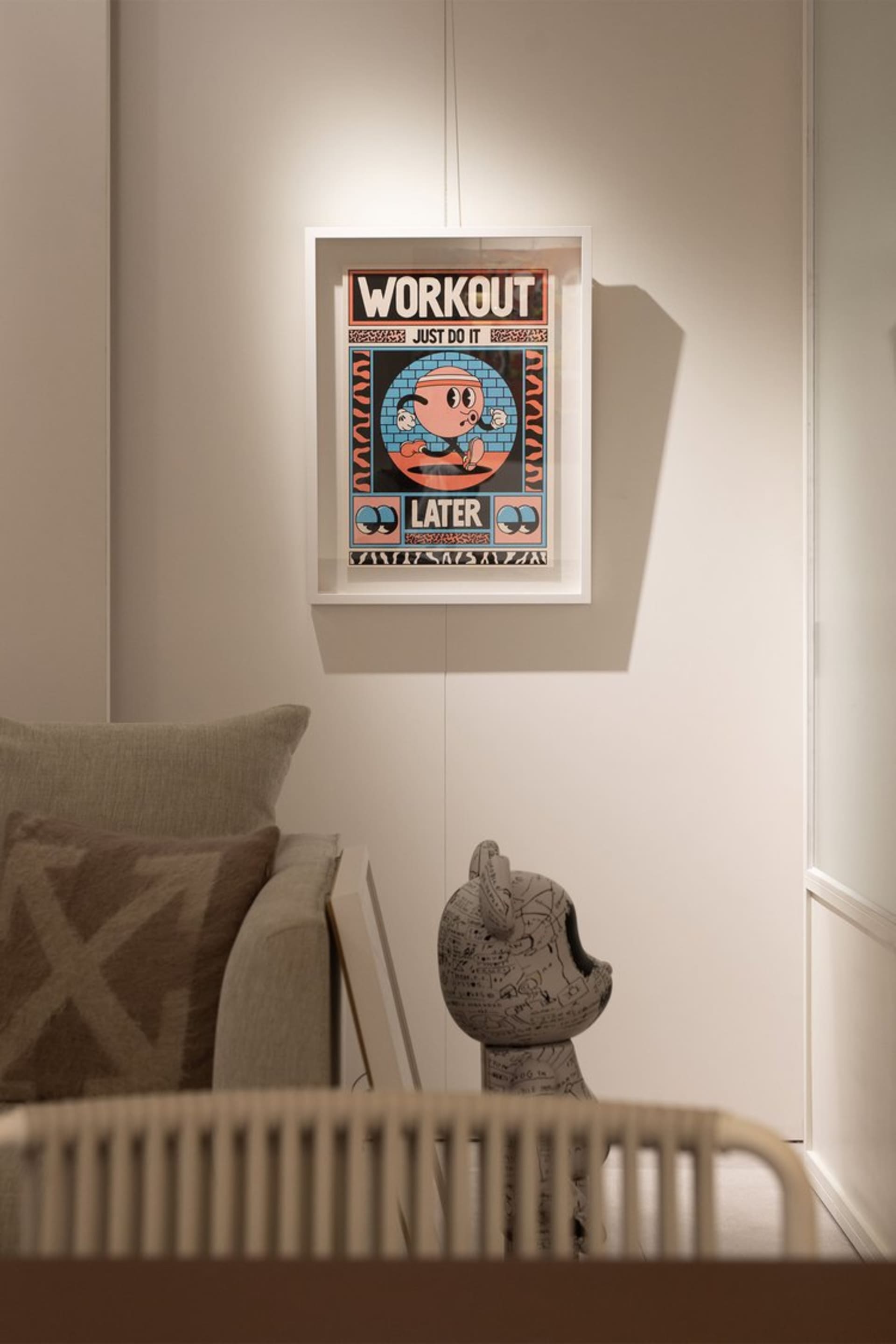 一張簡約海報，上面有卡通角色與「Workout Later」文字，裱框後掛在牆上。