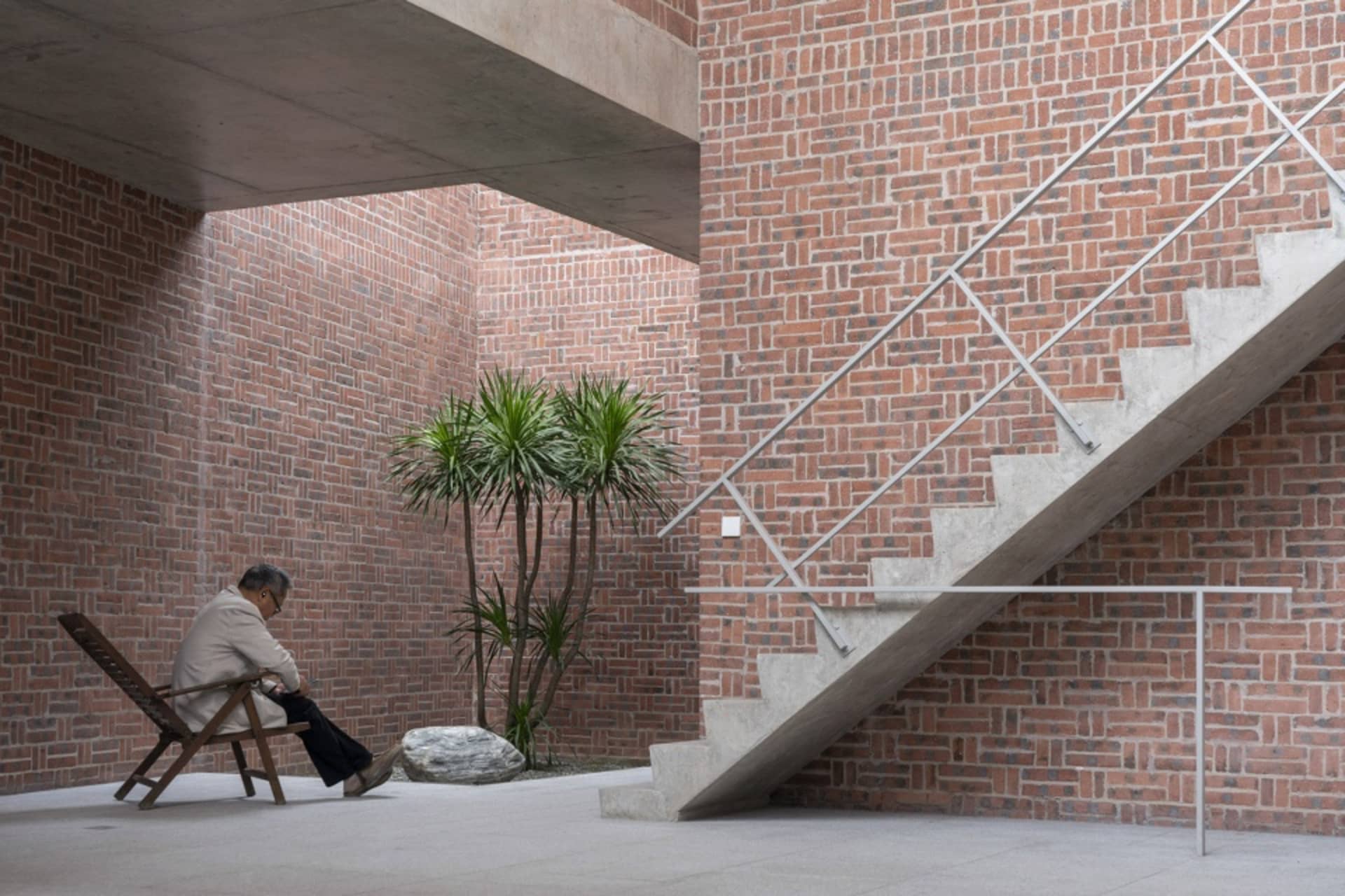 A modern concrete staircase with a brick wall in a serene indoor setting.