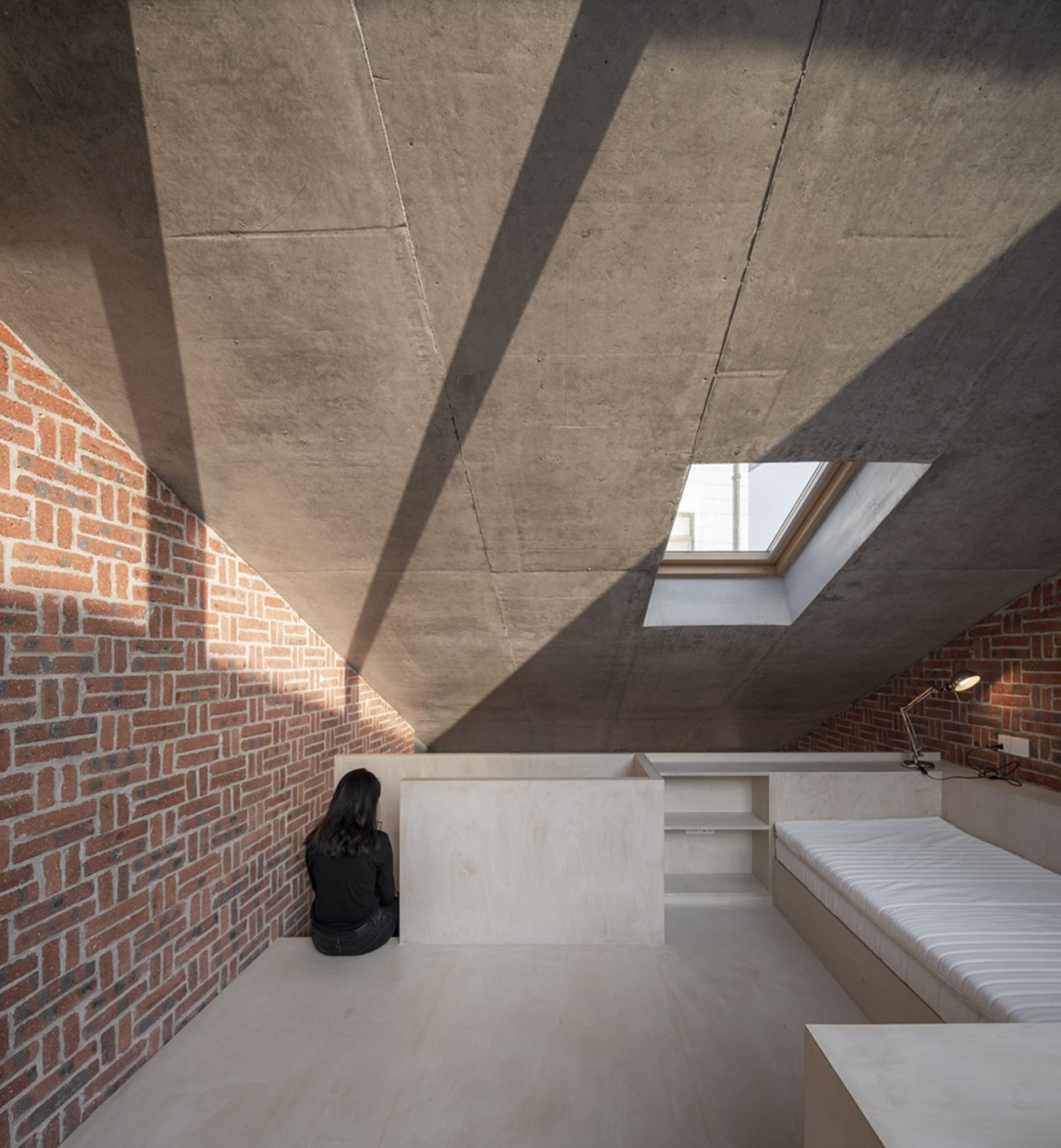Modern minimalist living room featuring exposed brick walls and concrete ceiling.