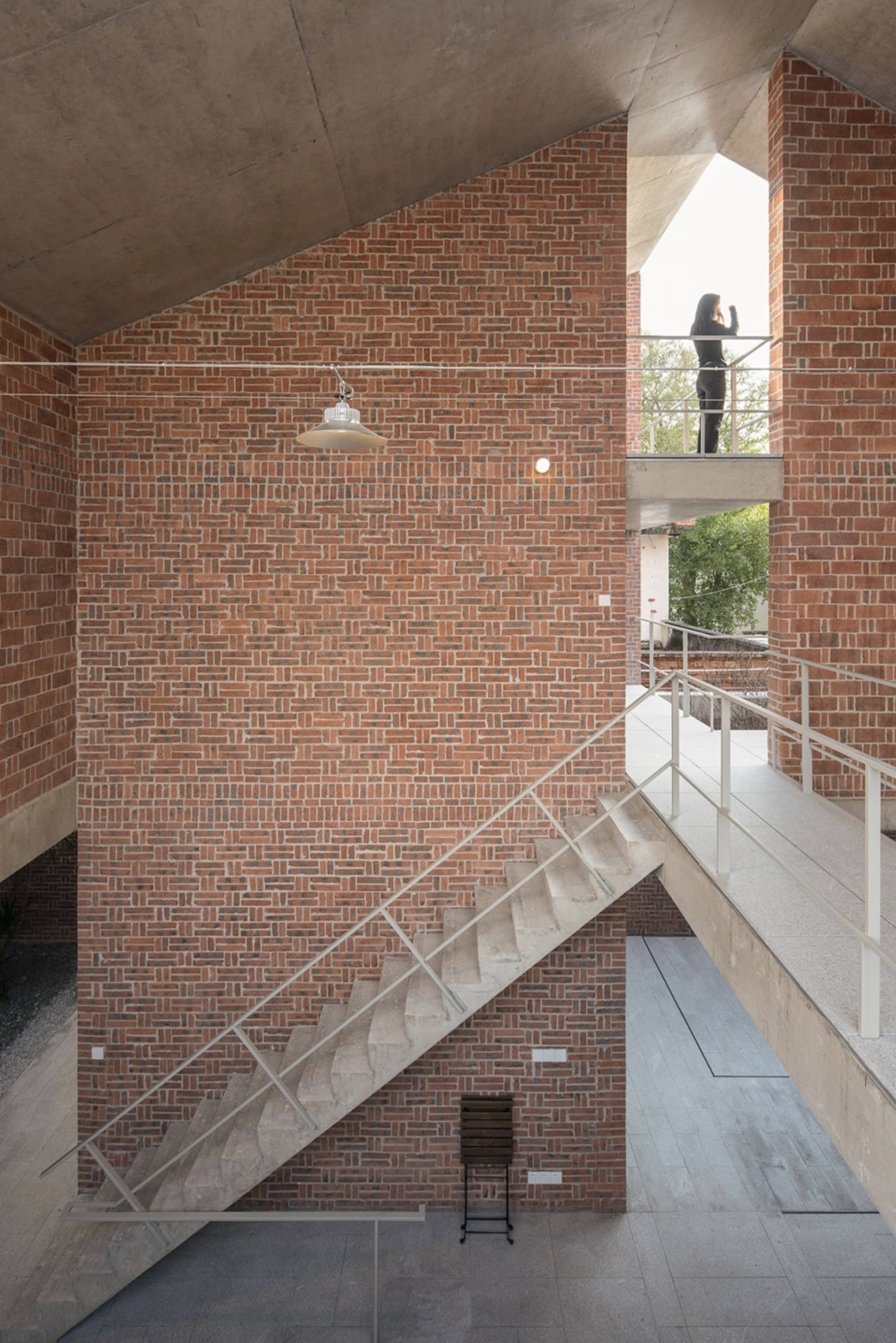 A modern industrial staircase with brick walls and concrete steps and railings