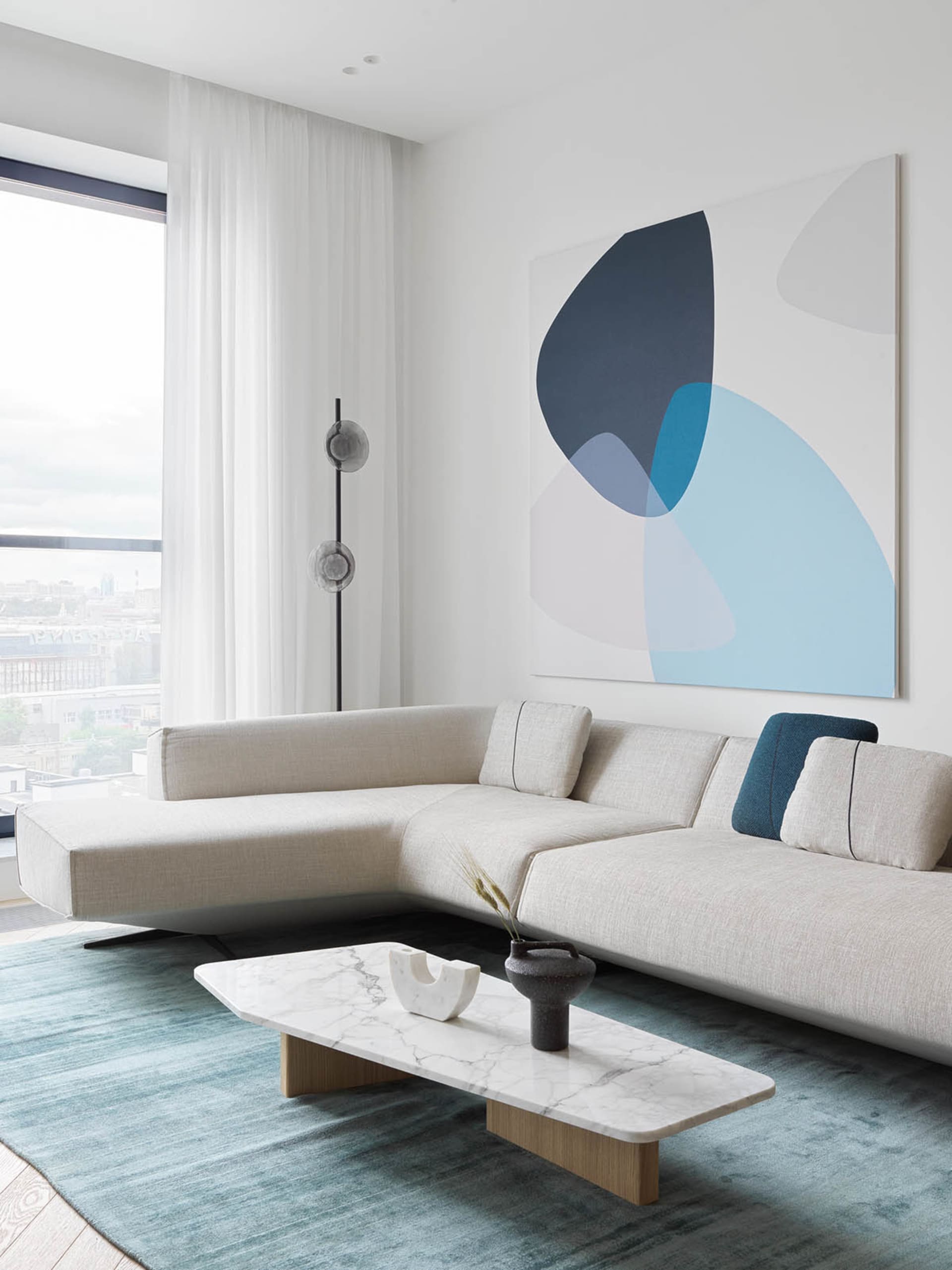 A modern living room featuring contemporary furniture with a minimalist aesthetic, including a white sectional sofa, a marble