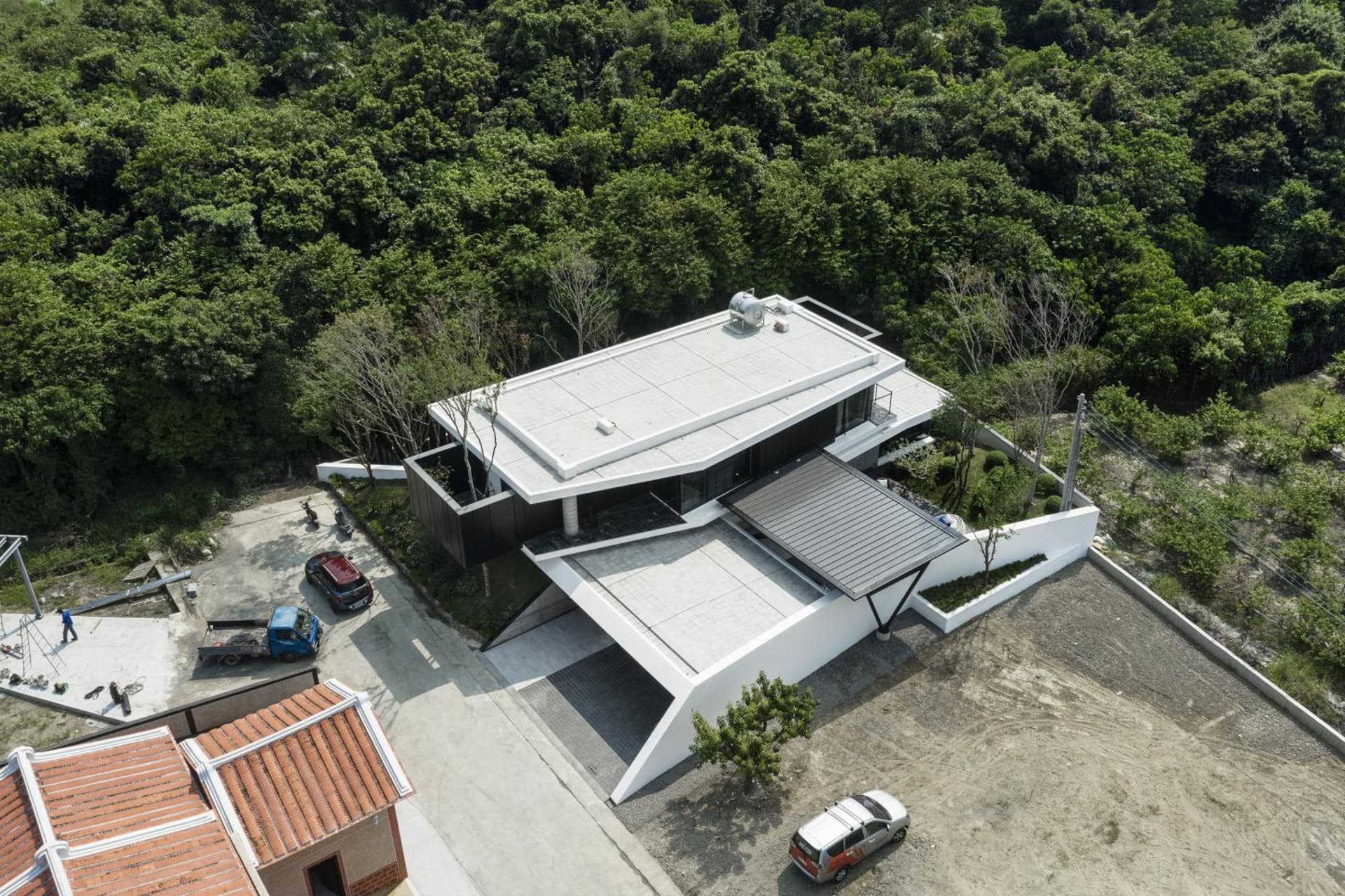 一棟擁有白色與玻璃外觀的現代住宅,周圍環繞著樹木。