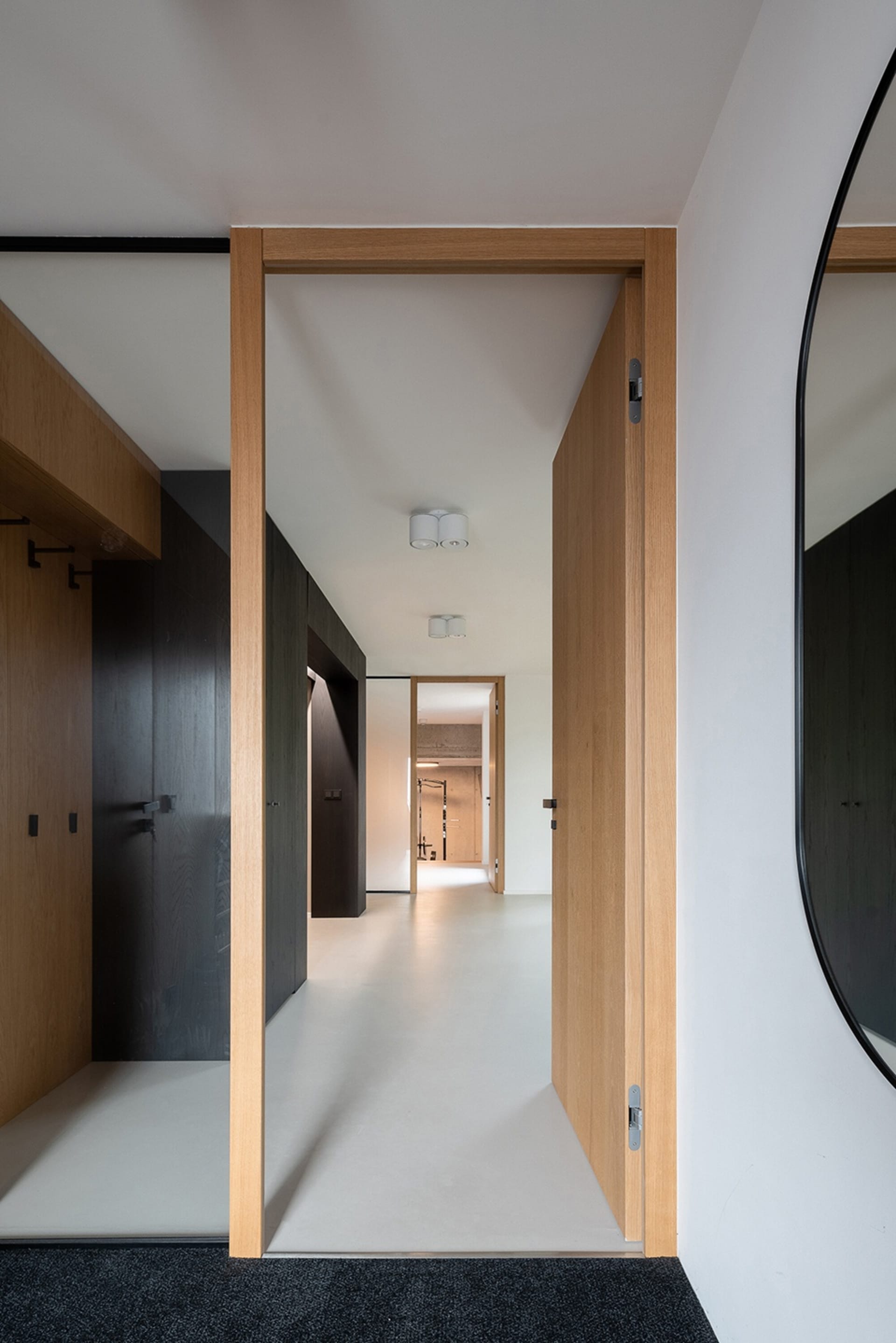 A modern interior corridor with light-colored hardwood floors and dark wooden cabinets.