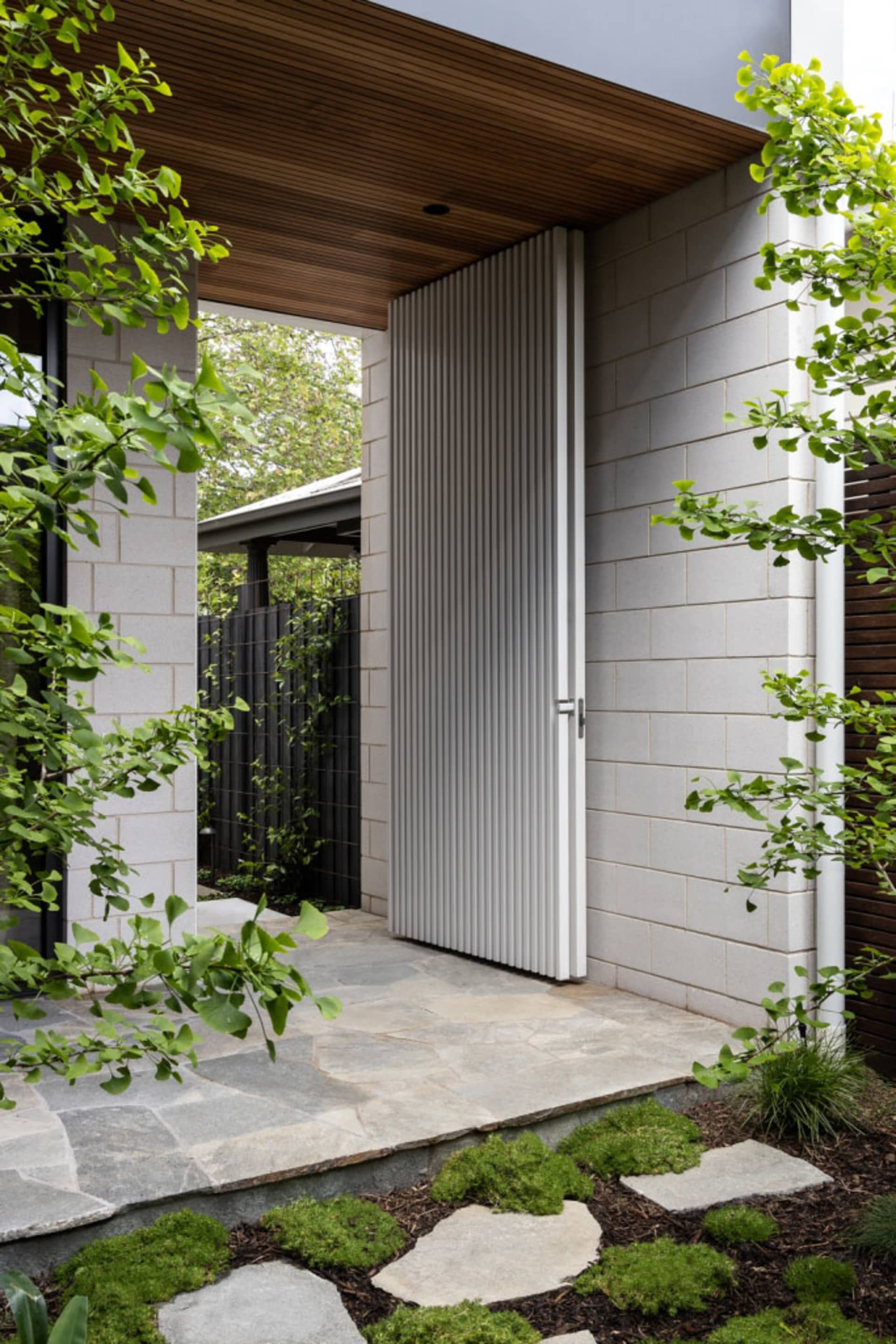 A modern entrance with concrete walls and a wooden roof structure.