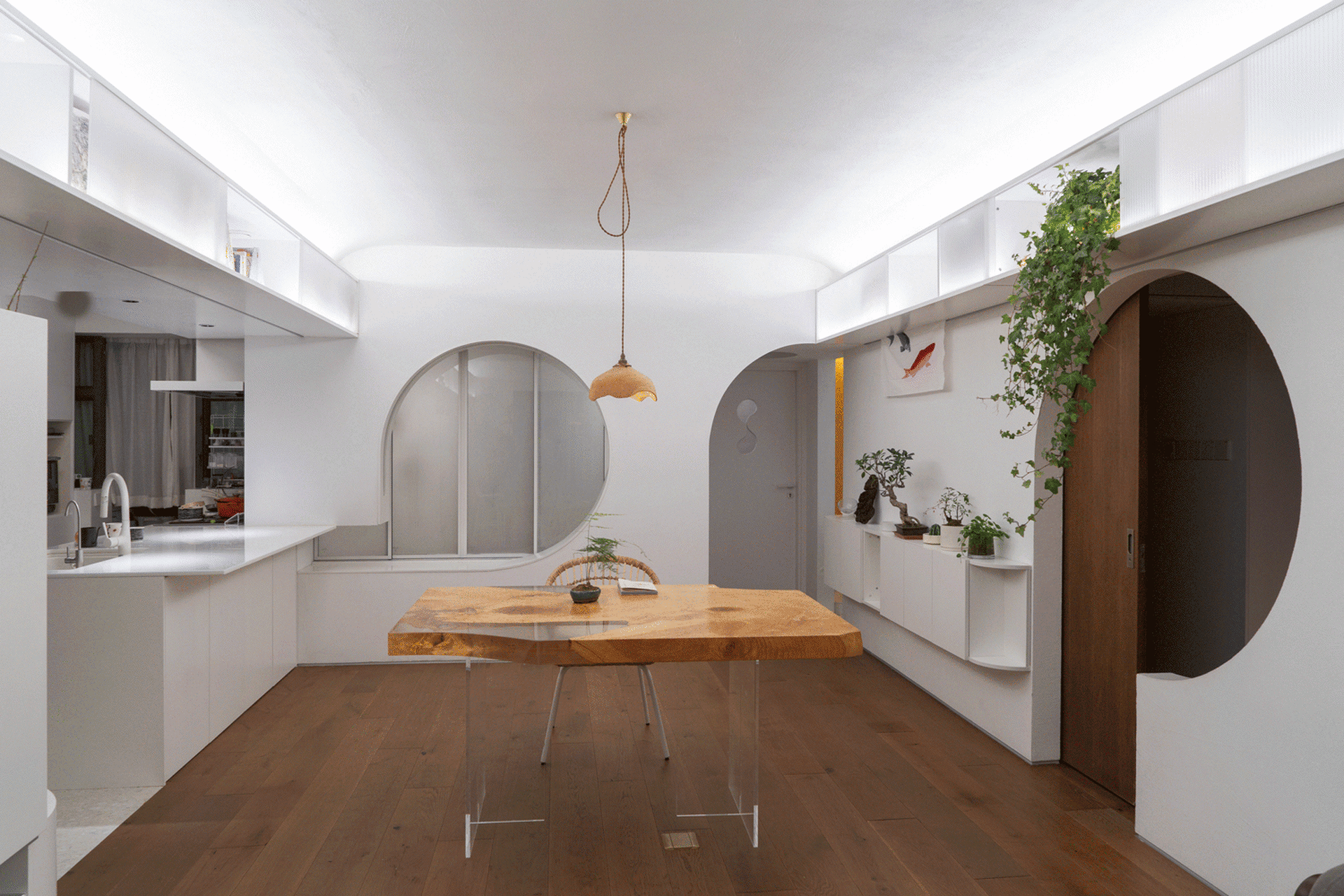 Minimalist residential kitchen featuring wooden table, glass pendant light, and white walls and cabinets.