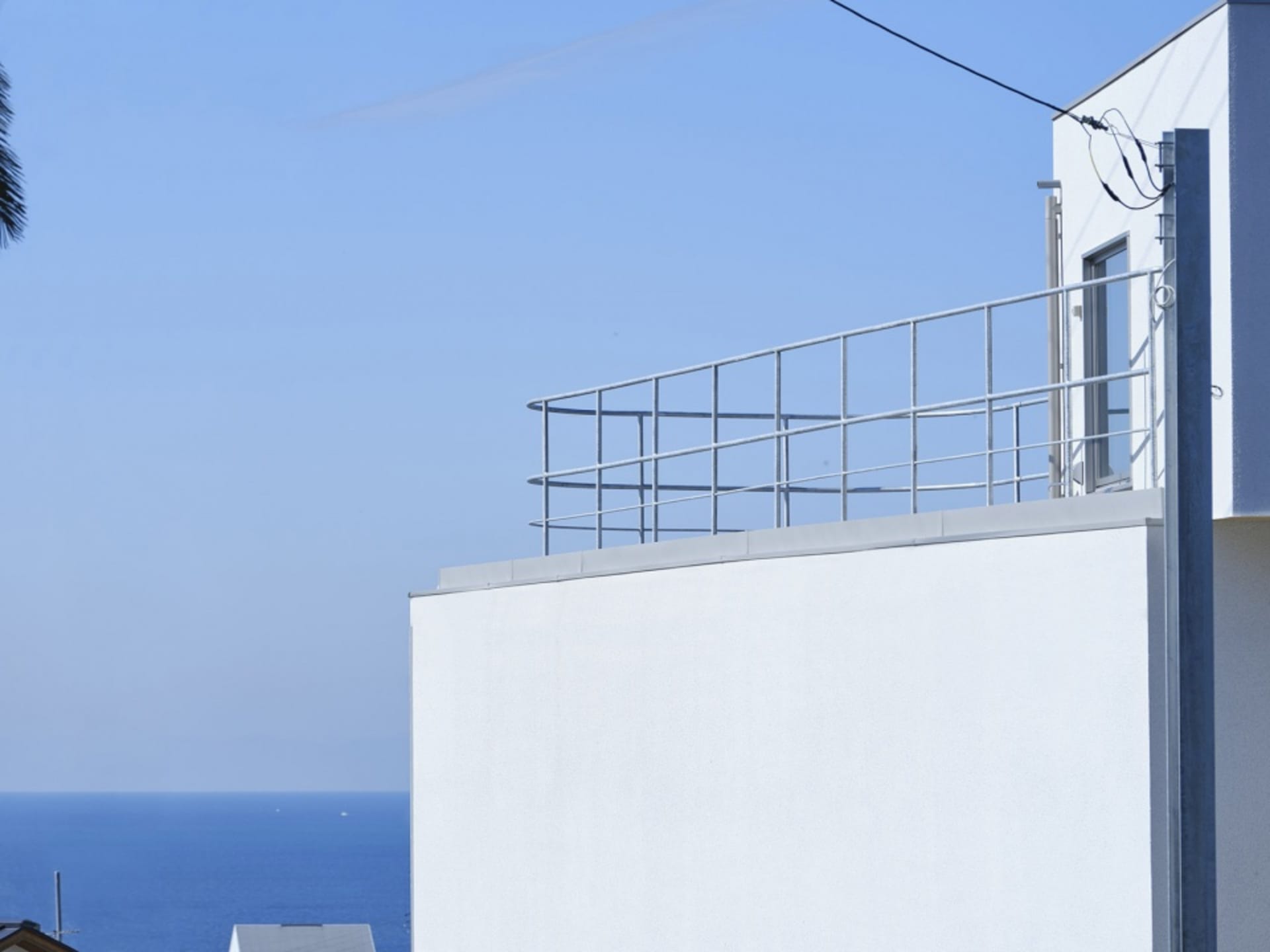A modern white residential exterior with a concrete facade and white railings.