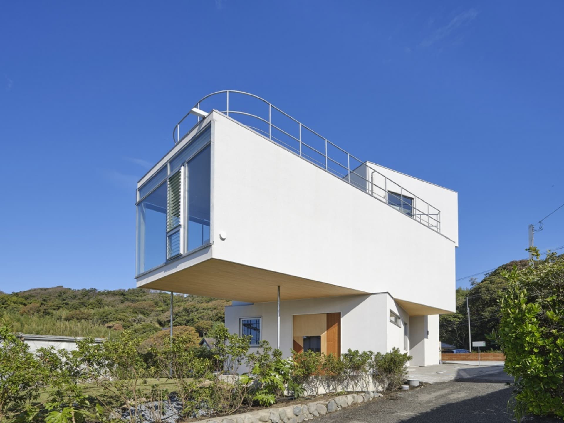 A modern house with a white exterior and large glass windows.