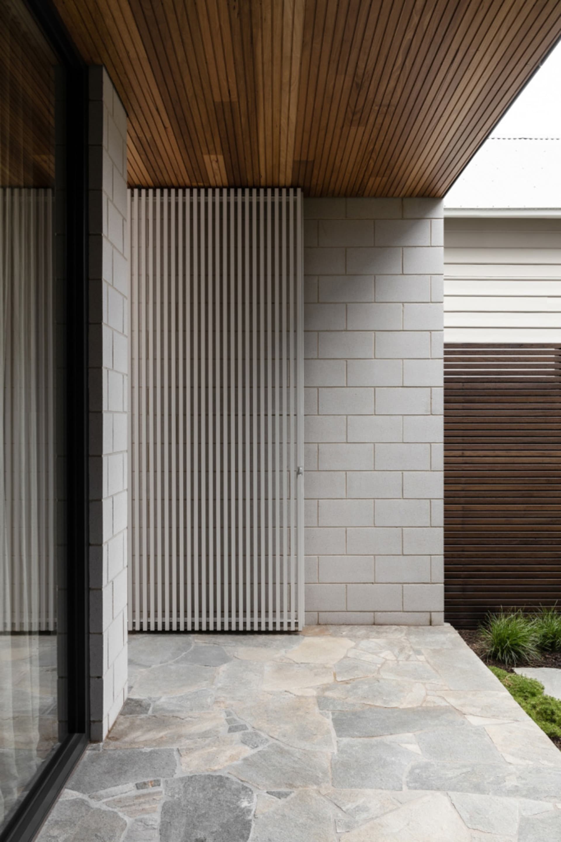 Modern residential entryway featuring stone, brick, and wood materials.