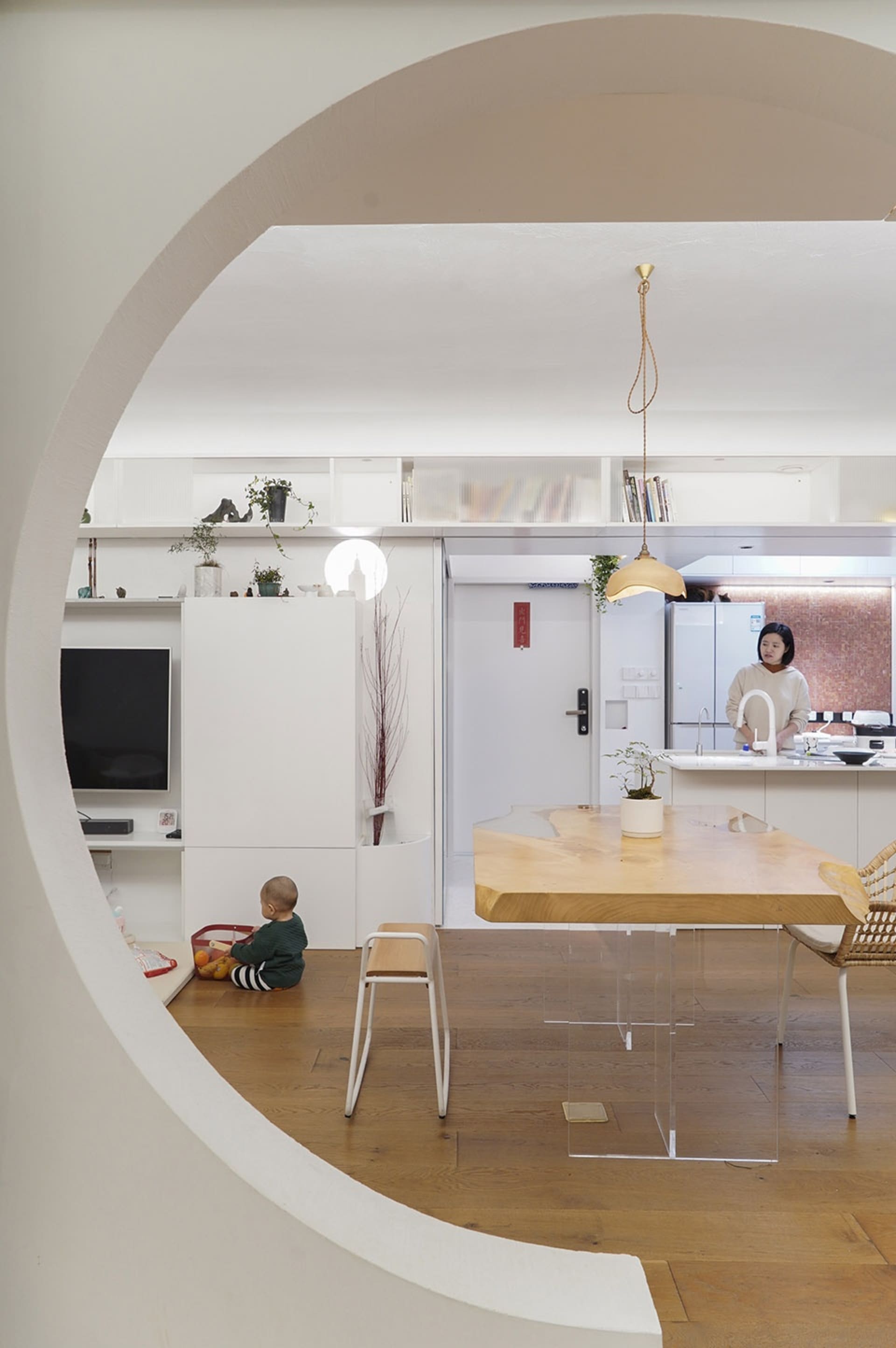 A modern residential interior featuring a minimalist design with white walls, wooden furniture, and glass elements.